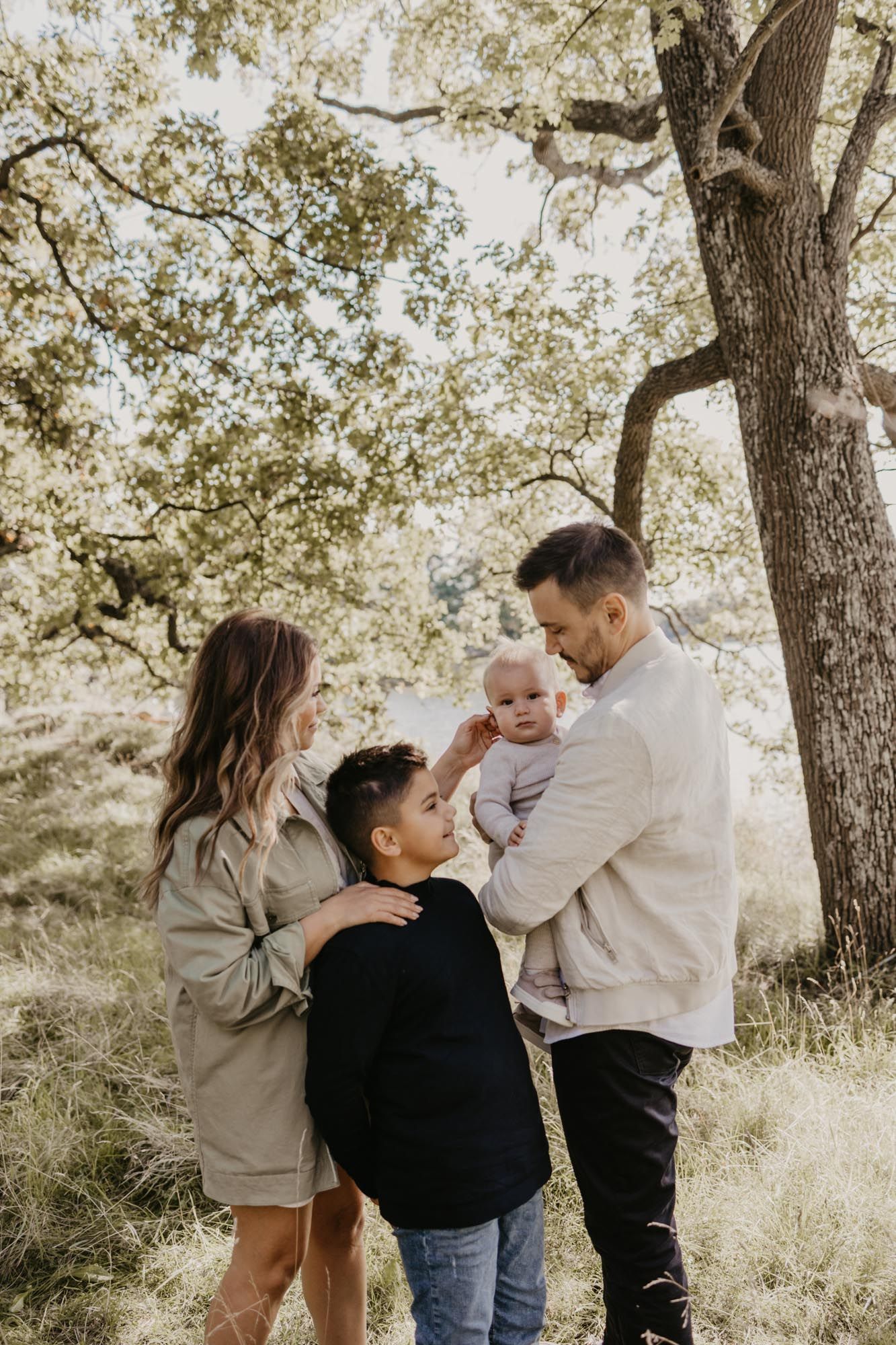 Intimate family gathering under a large oak tree in warm sunlight.
