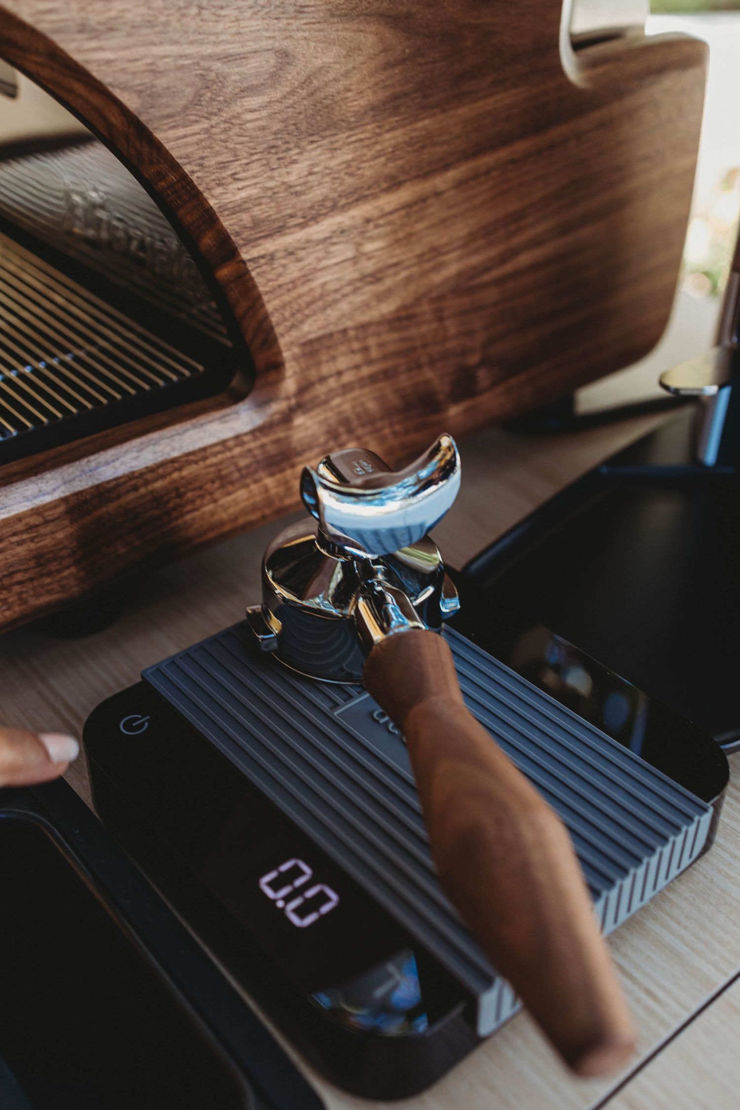 Coffee tamping station with professional equipment on wooden surface.