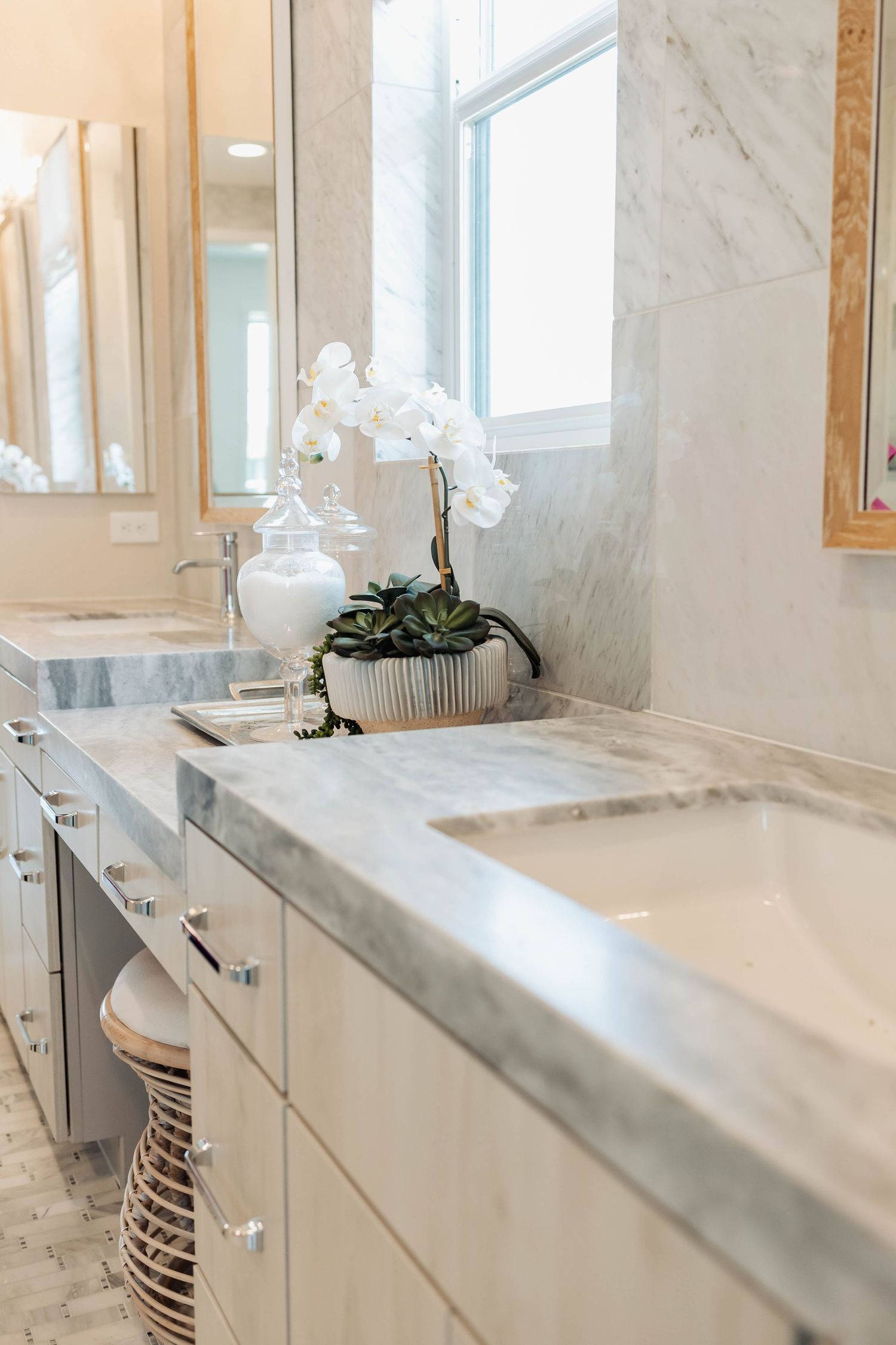 Elegant bathroom vanity with marble countertops and gold-framed mirror.
