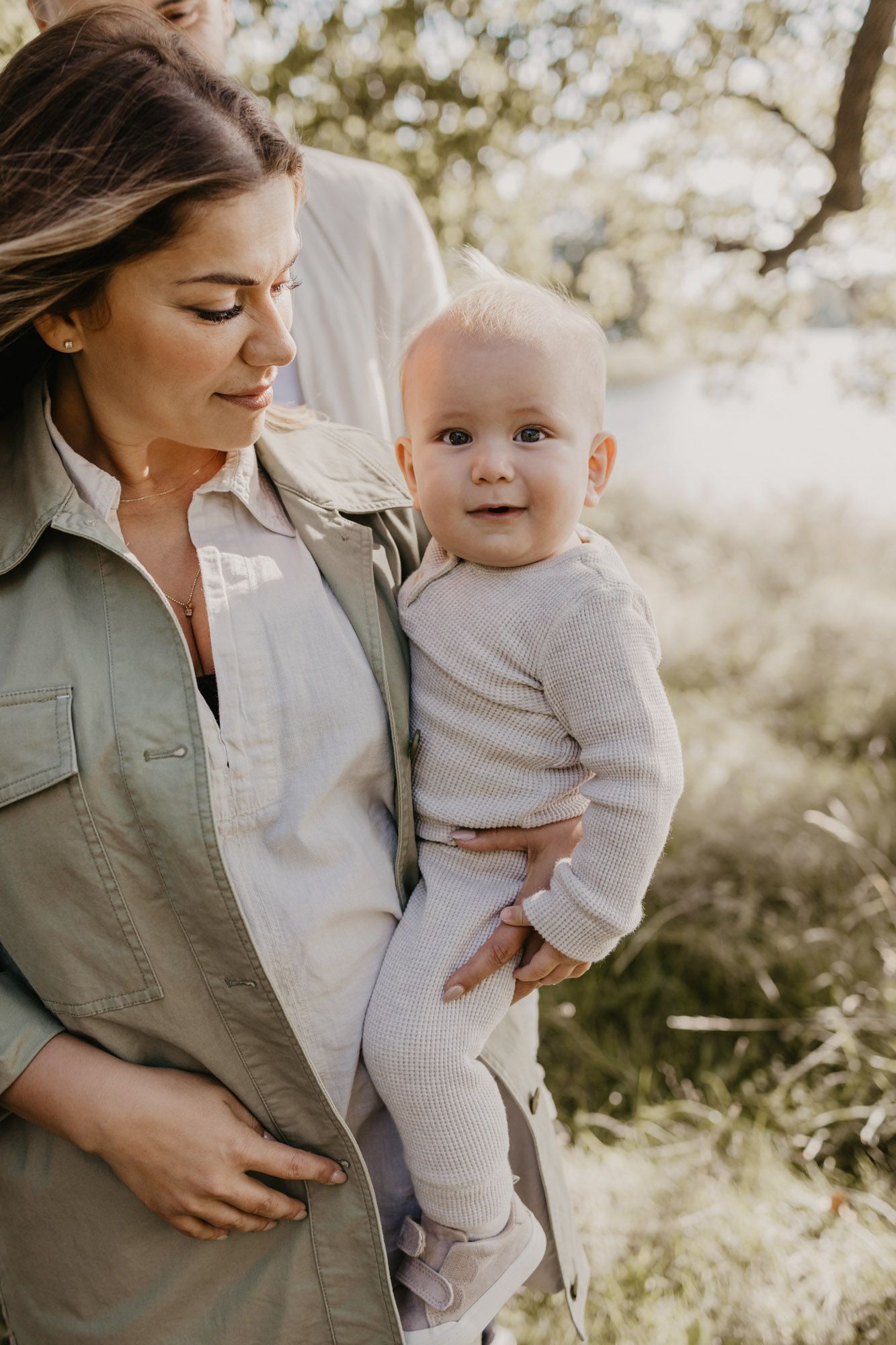 Intimate portrait of parent and baby in soft natural lighting outdoors.