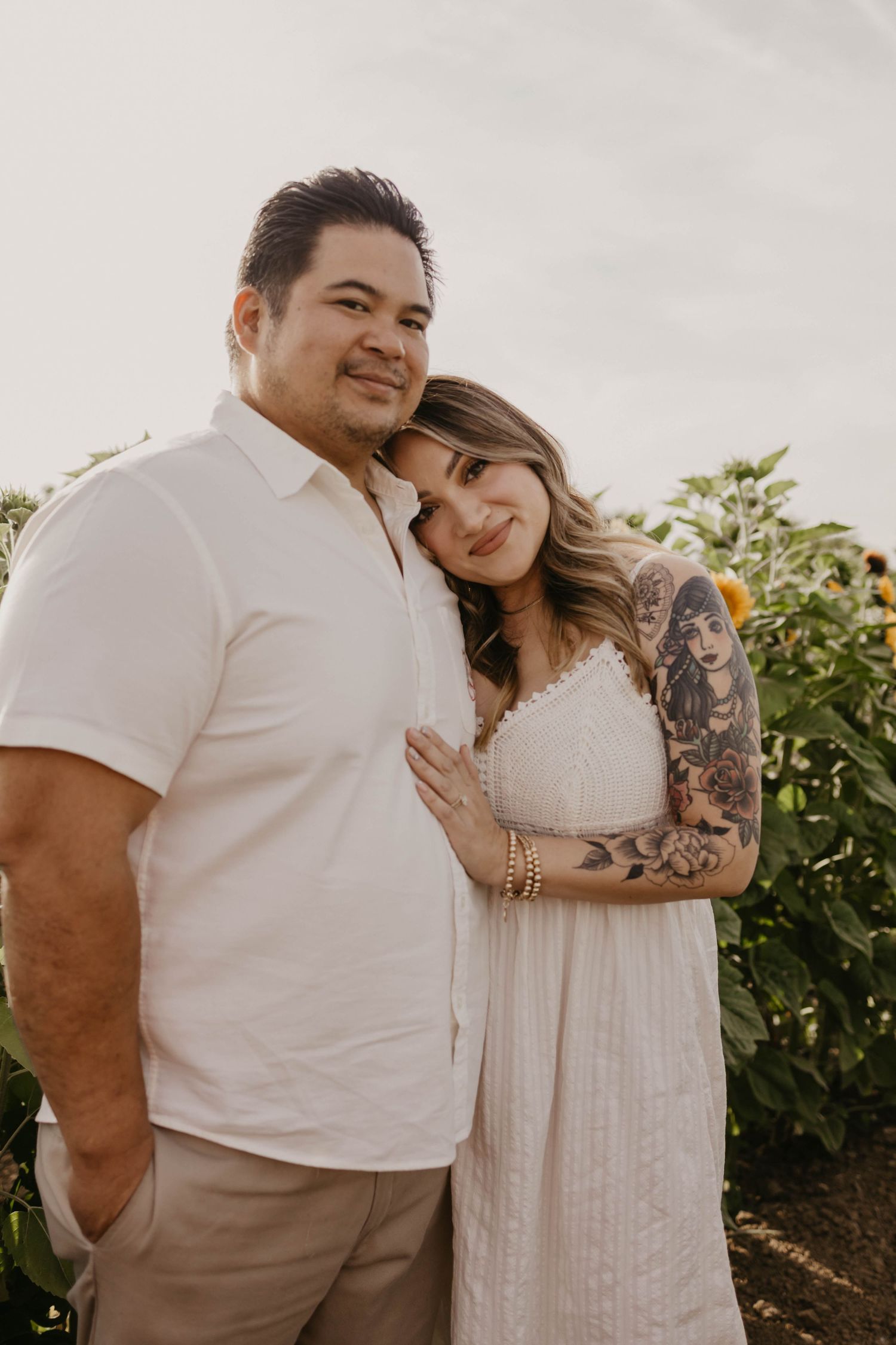 A couple shares tender moments and laughter while posing together in an outdoor garden setting.