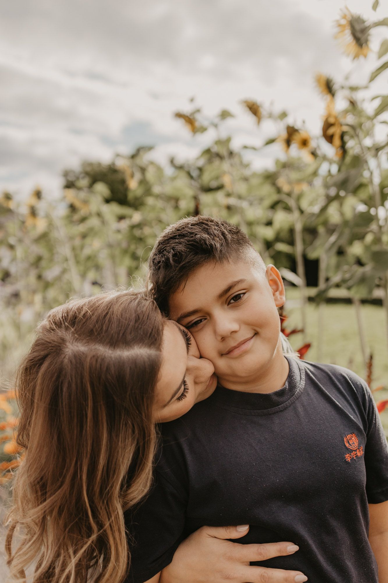 An affectionate moment captured in front of a sunflower garden.