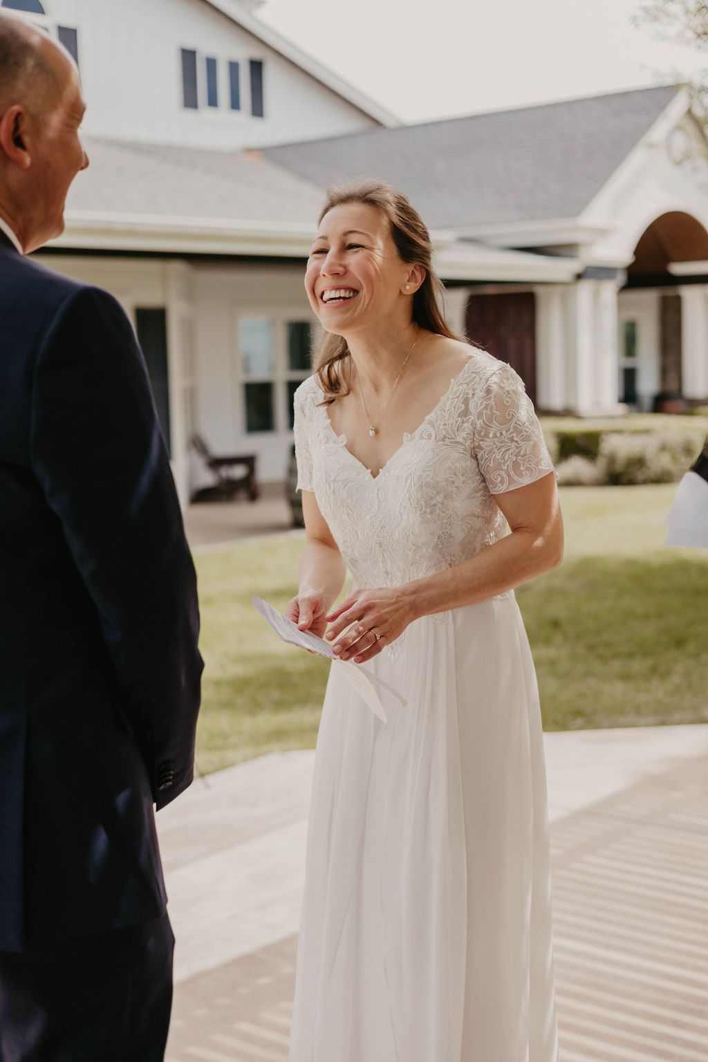 A joyous wedding ceremony moment shared on the porch of a white building.