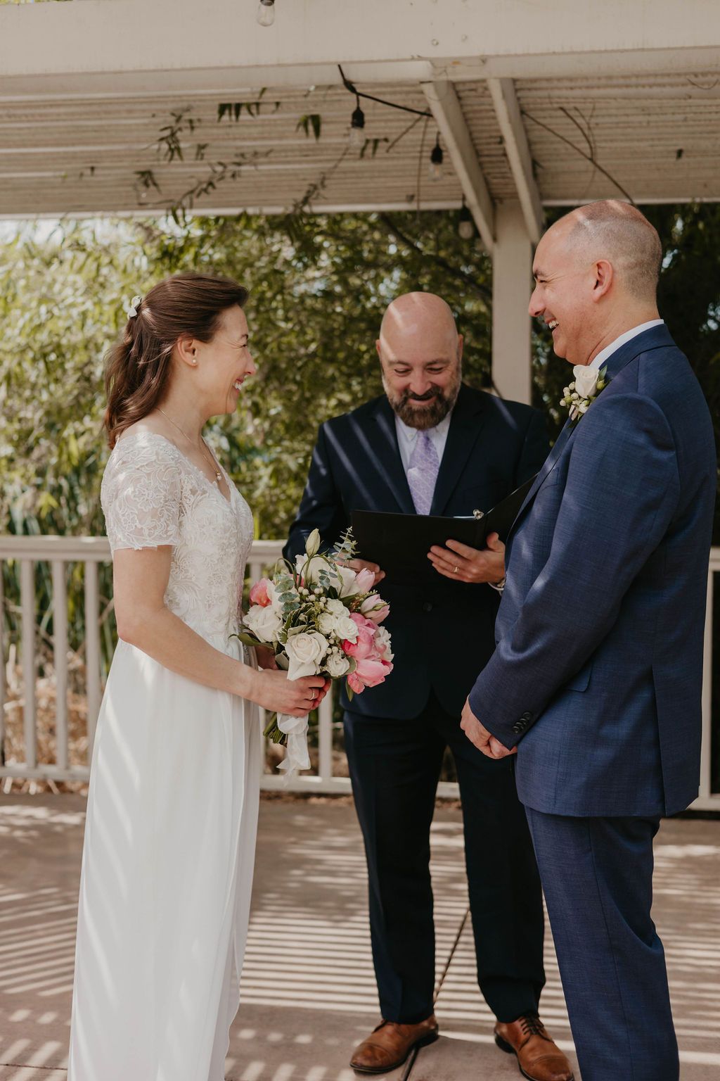 A couple exchanges vows with an officiant during an intimate outdoor wedding ceremony.