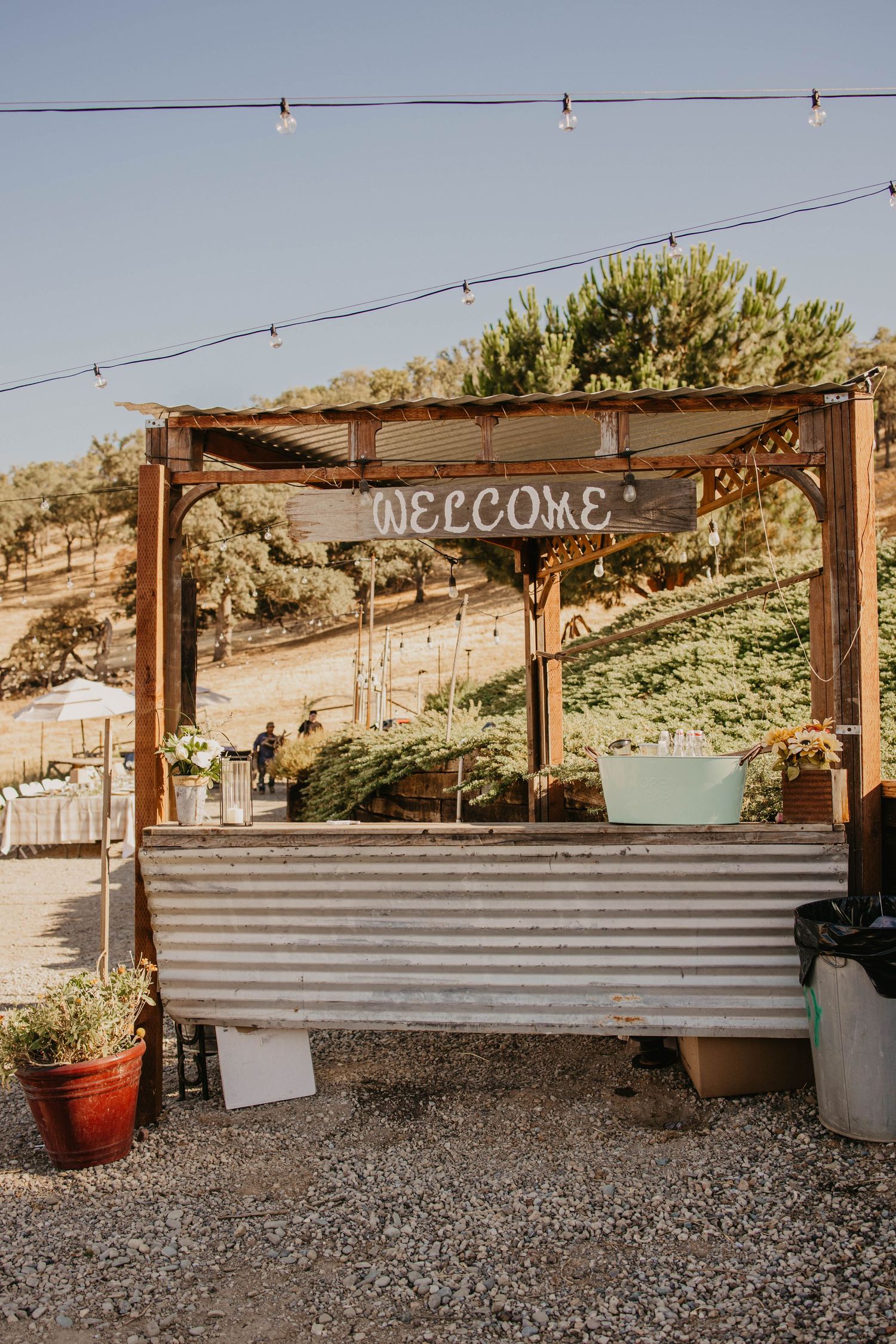 Rustic outdoor venue with wooden pergola and welcome sign.