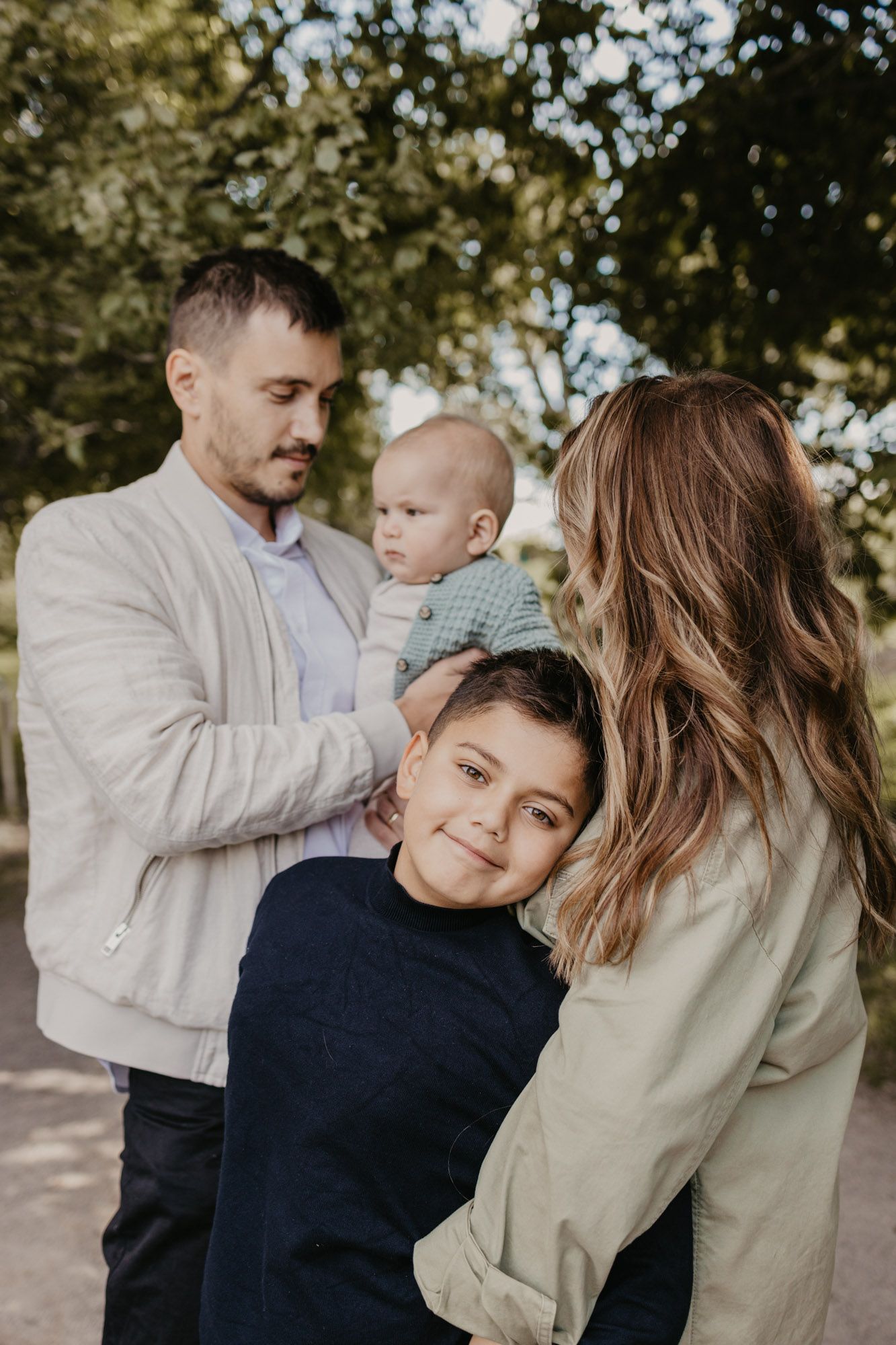 Outdoor family portrait showing tender moments between parents and children in soft lighting.