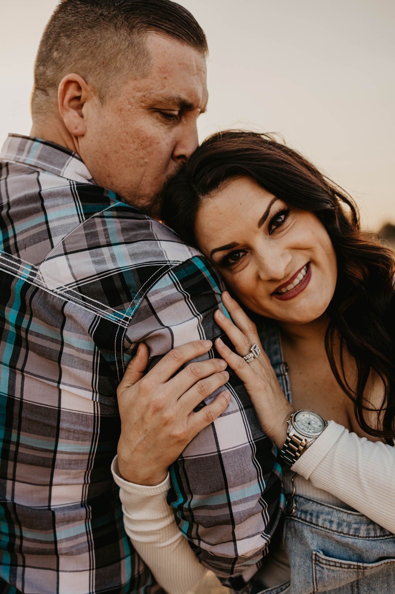 A couple shares a tender moment during their engagement photoshoot while wearing casual attire.