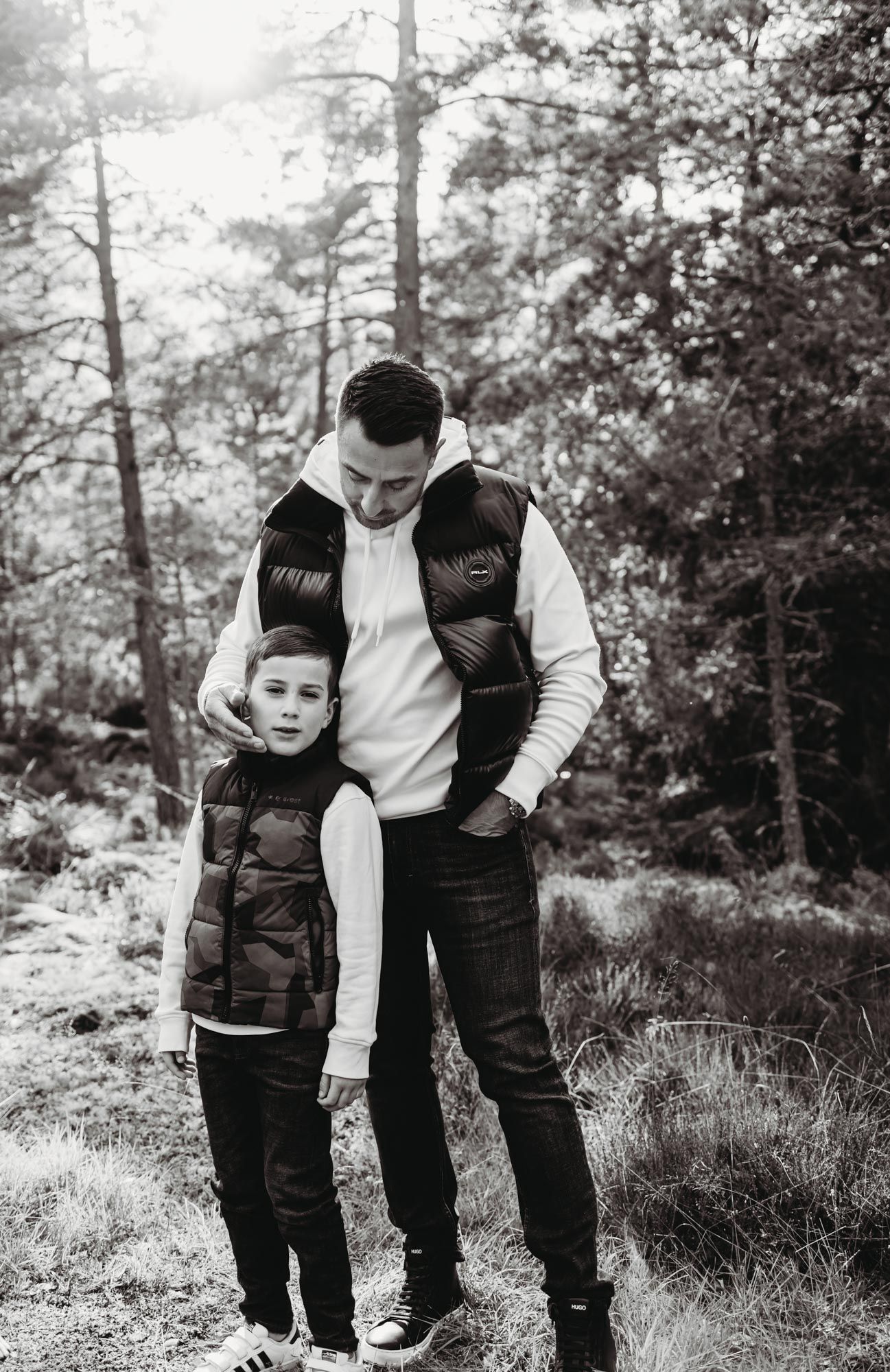A black and white portrait of two people in matching puffer vests outdoors.