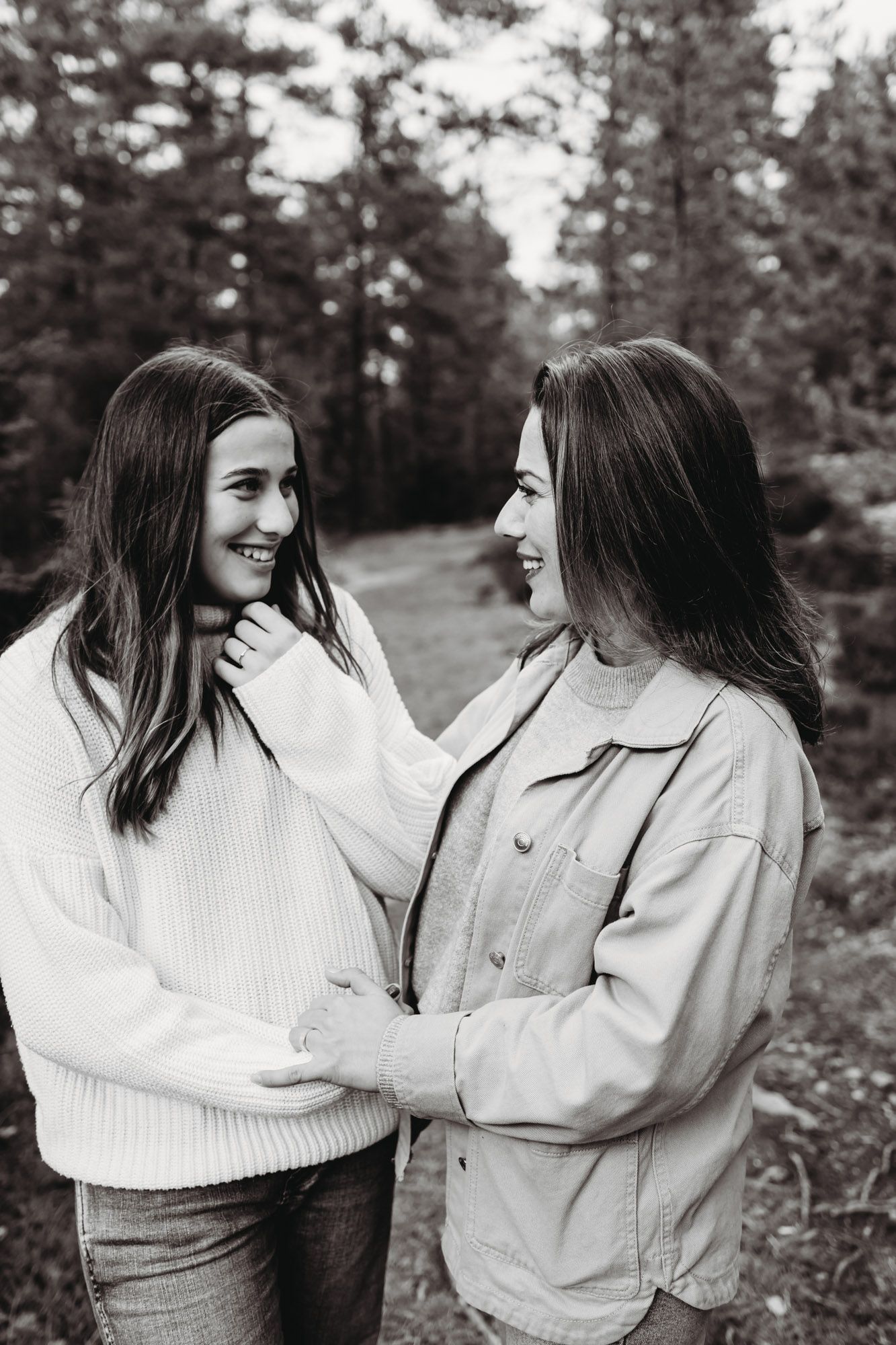 Black and white portrait of two people sharing a tender moment outdoors in casual winter wear.