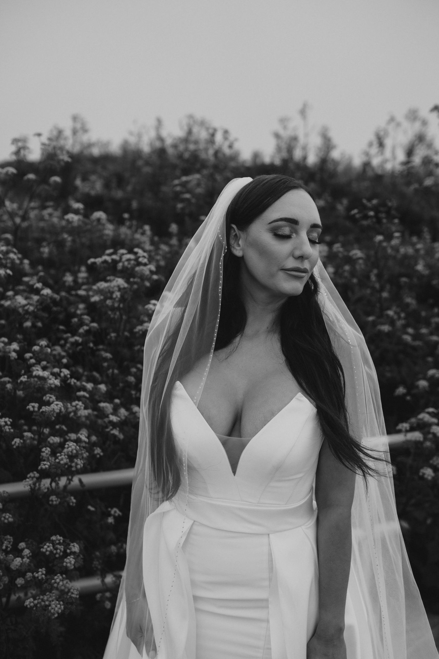 Black and white bridal portrait featuring a flowing veil and fitted wedding dress.