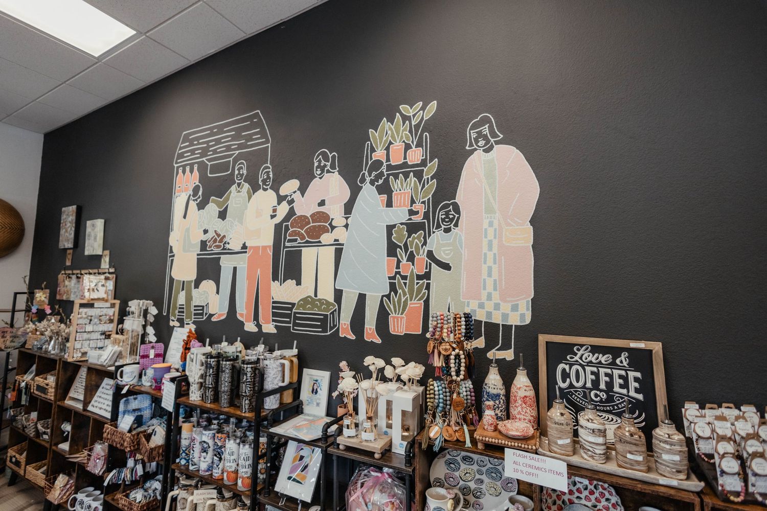 Whimsical wall mural of figures above retail shelves in a coffee shop.