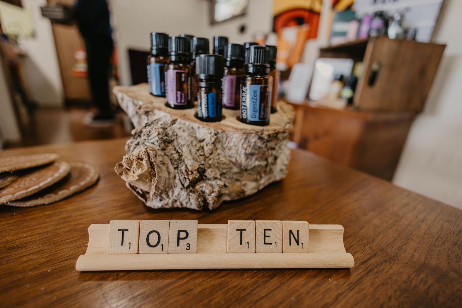 Wooden Scrabble tiles spelling 'TOP TEN' on rustic surface.
