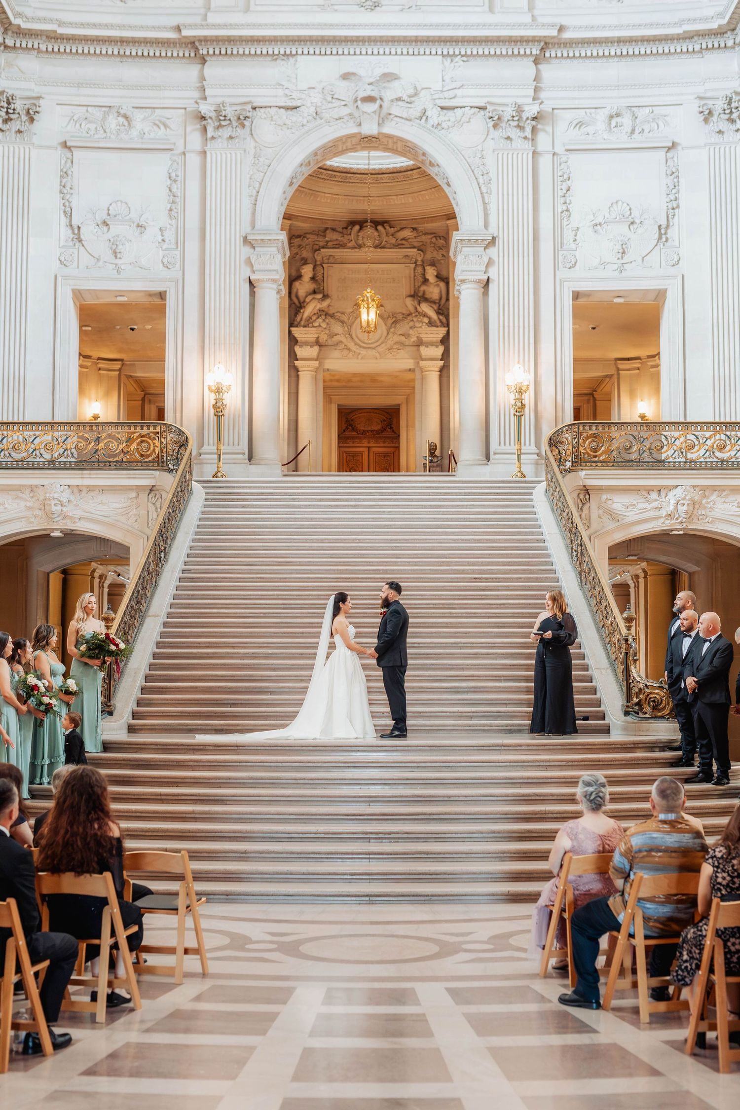 Bride and groom exchange vows on the grand staircase of San Francisco City Hall during an elegant wedding ceremony.