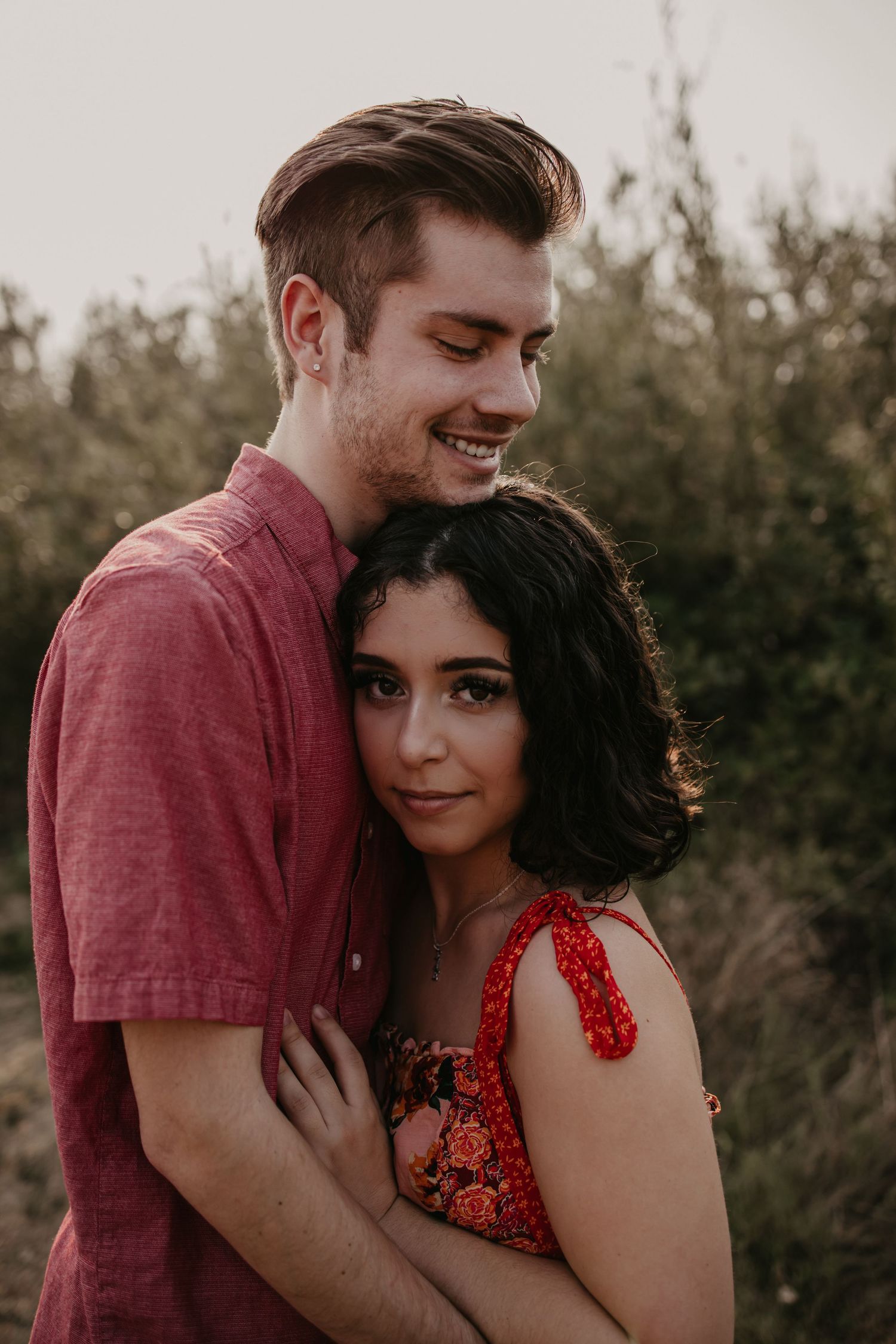 A couple in burgundy and red outfits share intimate moments during a photo session.