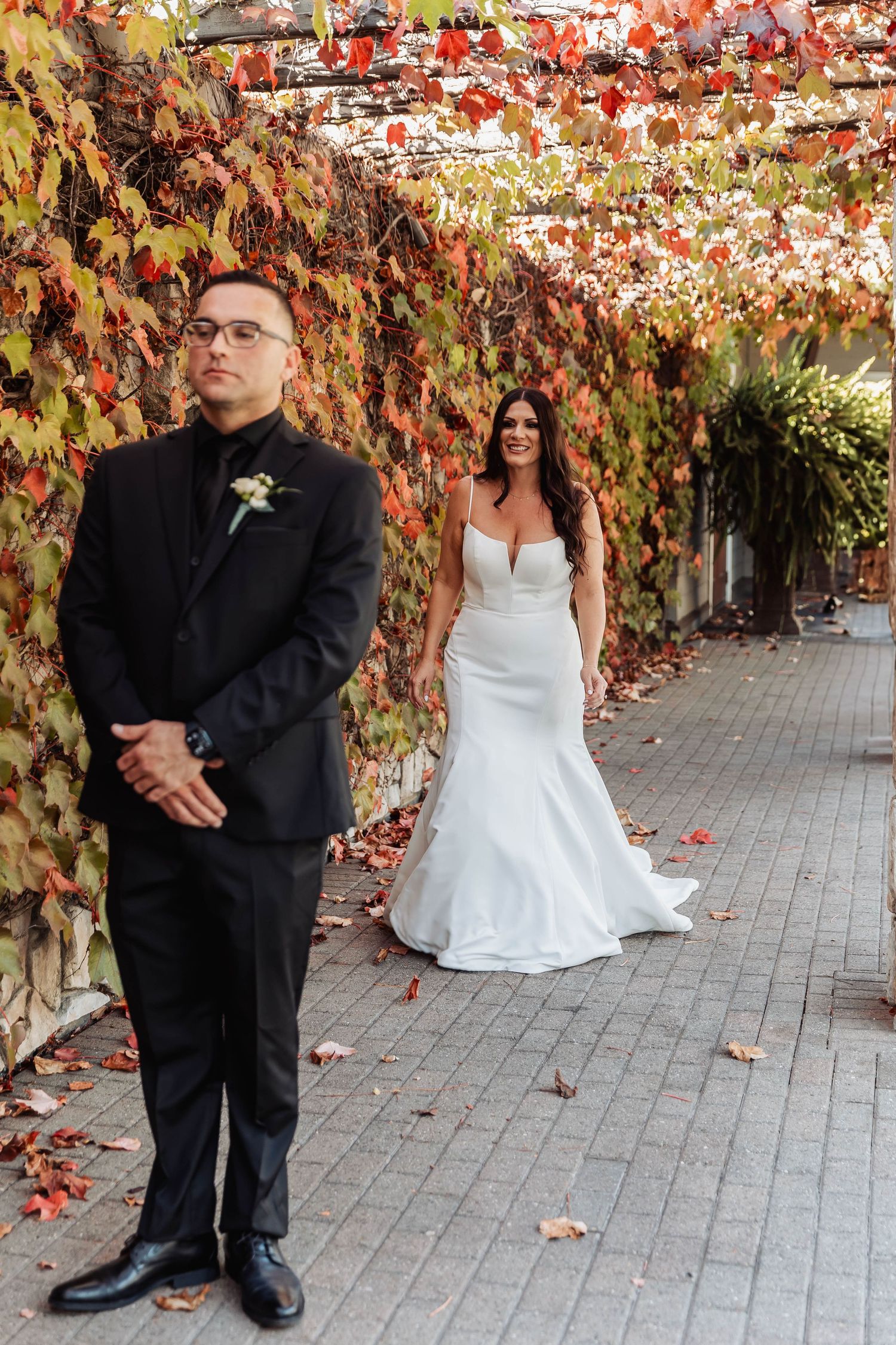 Wedding couple posing playfully against autumn foliage backdrop.