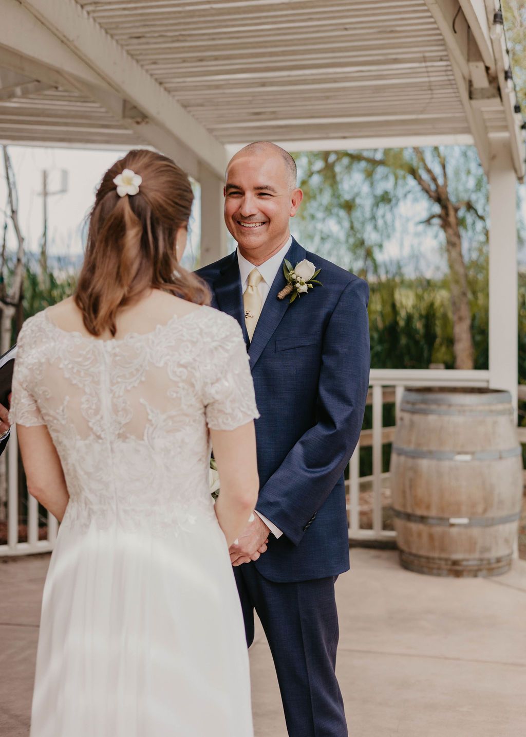A tender moment between a couple at their outdoor wedding with rustic barrel decor.