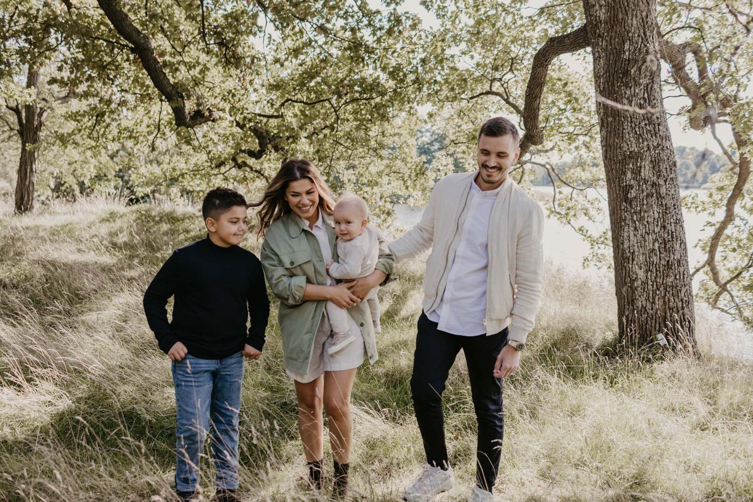 Family laughing together during a candid moment in a natural outdoor setting.