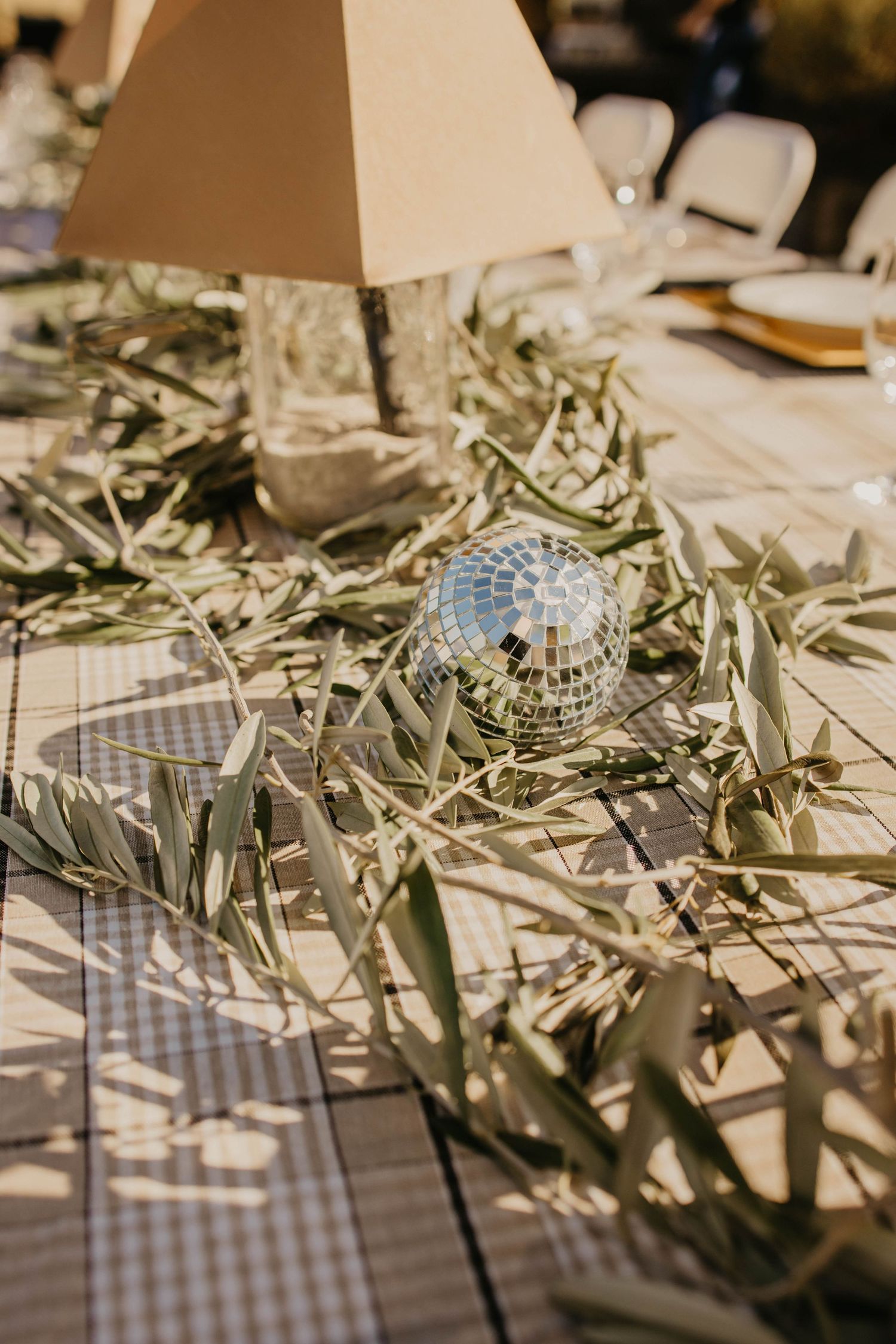 Rustic table setting with olive branches and checkered tablecloth creating an elegant Mediterranean atmosphere.
