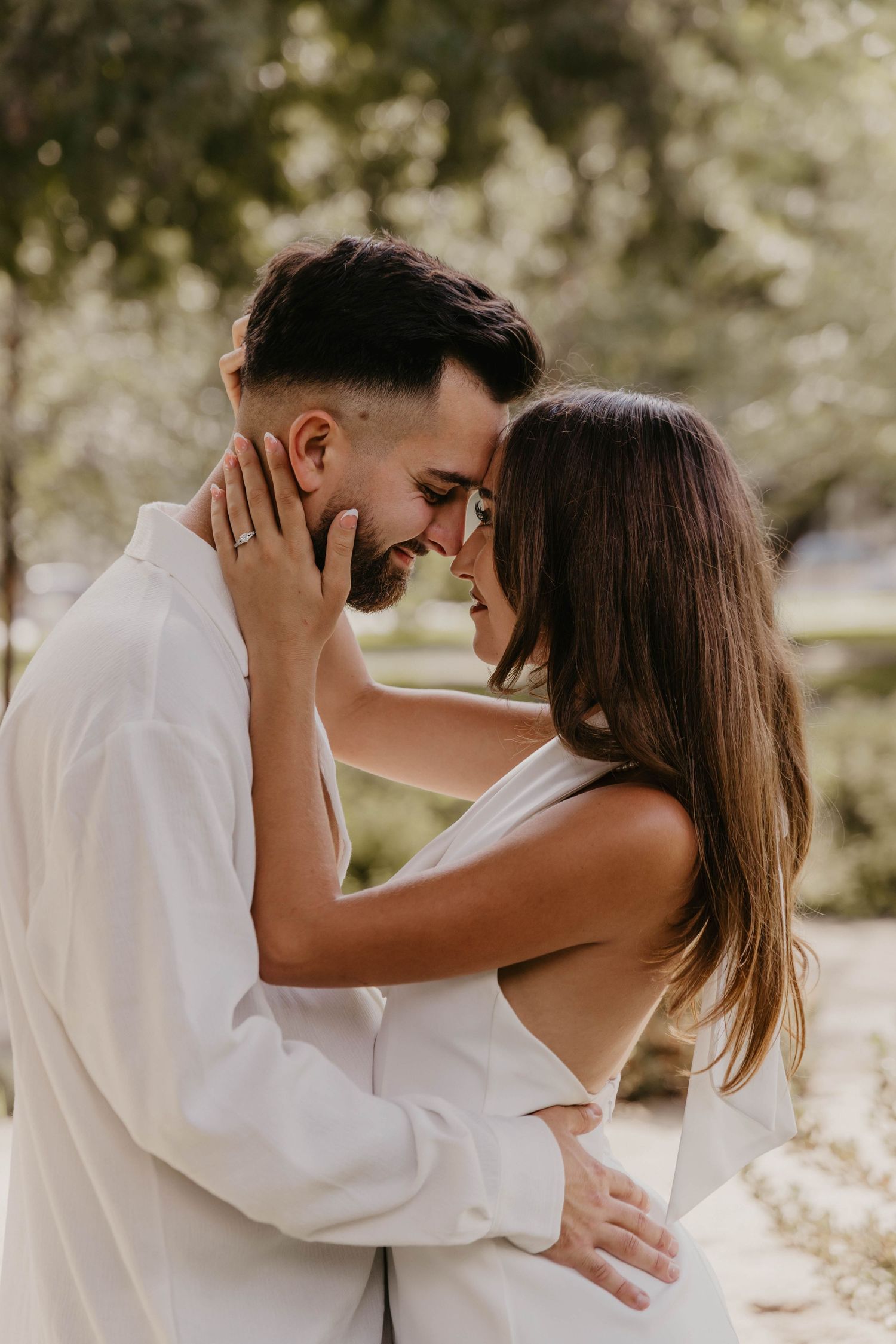 Intimate couple portraits in white outfits against natural outdoor background.