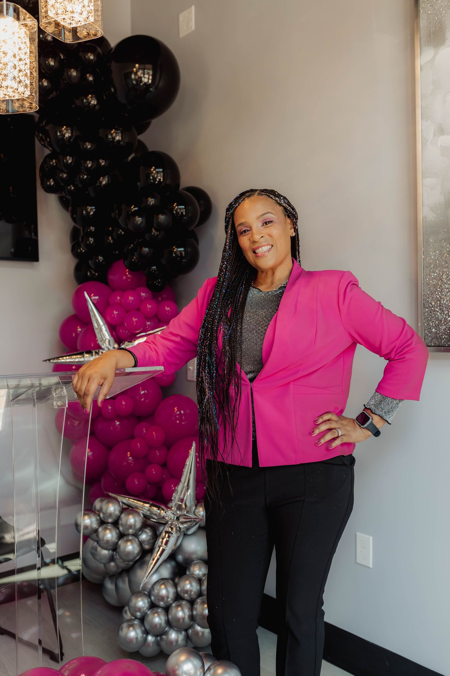 Vibrant studio portraits featuring a hot pink blazer and black balloons as decorative backdrop elements.