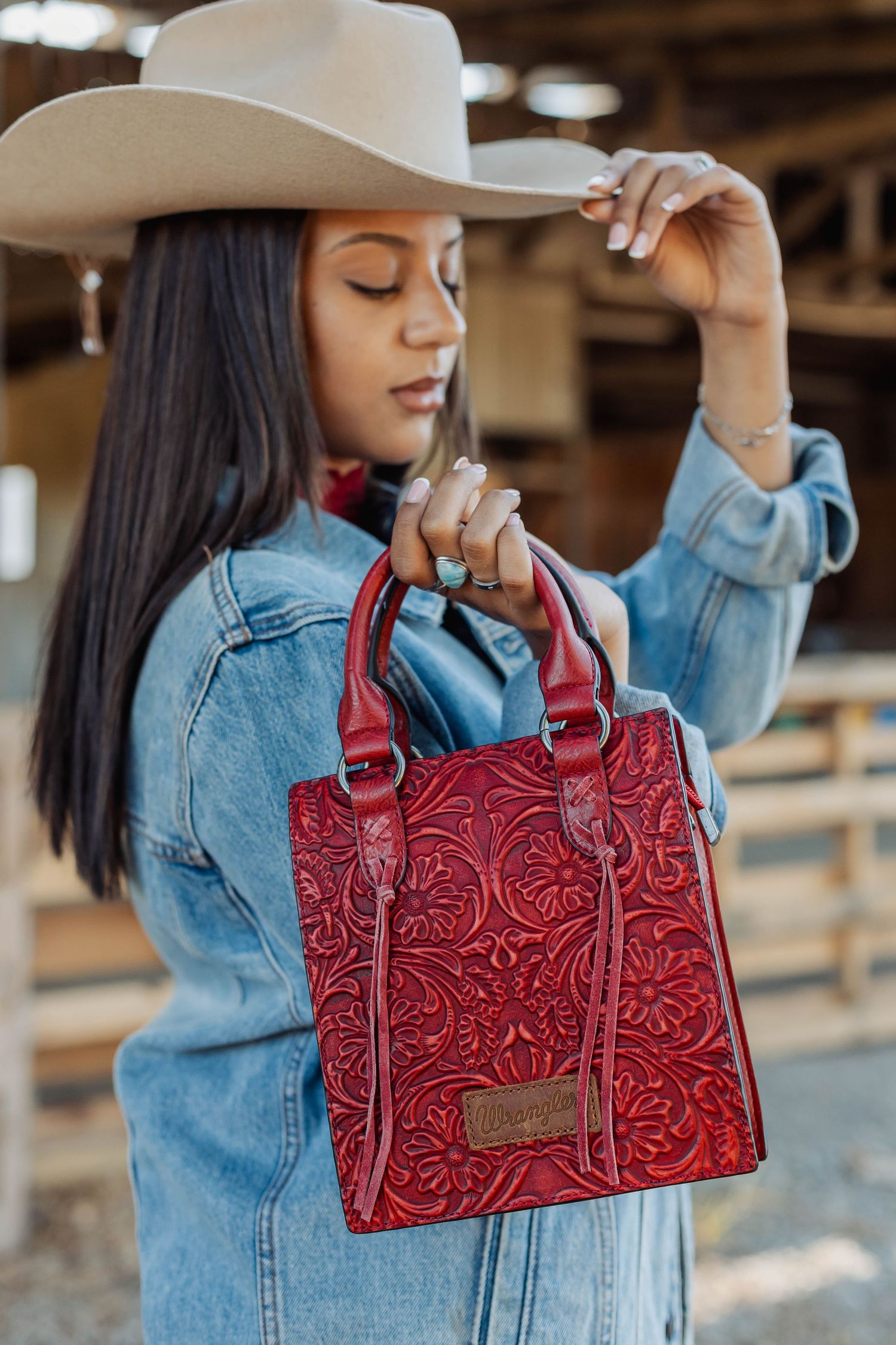 Red tooled leather handbag styled with denim jacket and western hat.