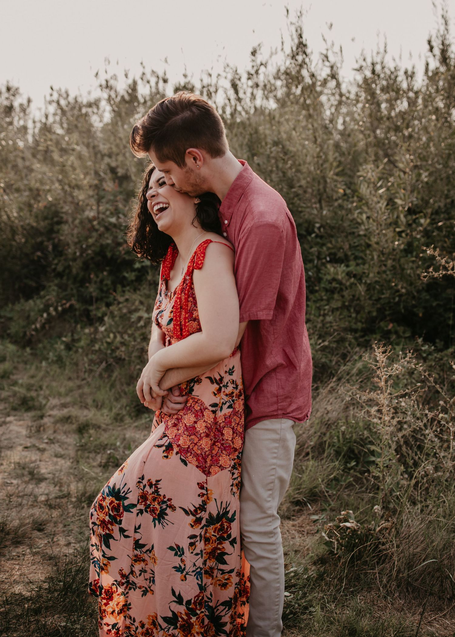 A romantic couple shares an intimate moment against a backdrop of wild brush during golden hour.
