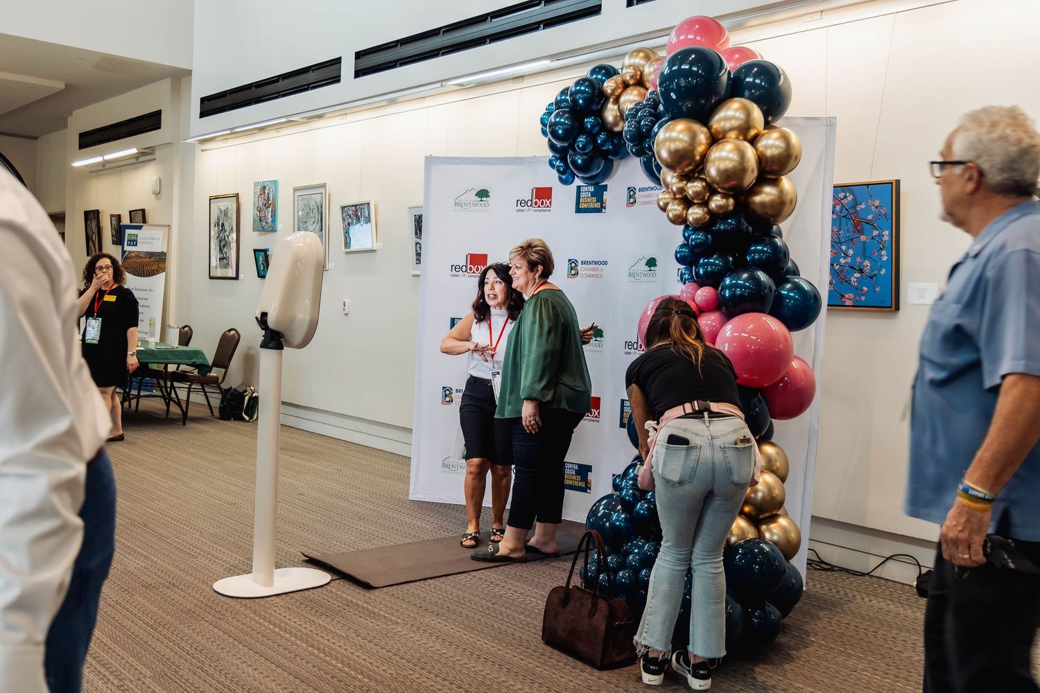Event space decorated with elegant black and gold balloon arch display near art gallery walls.