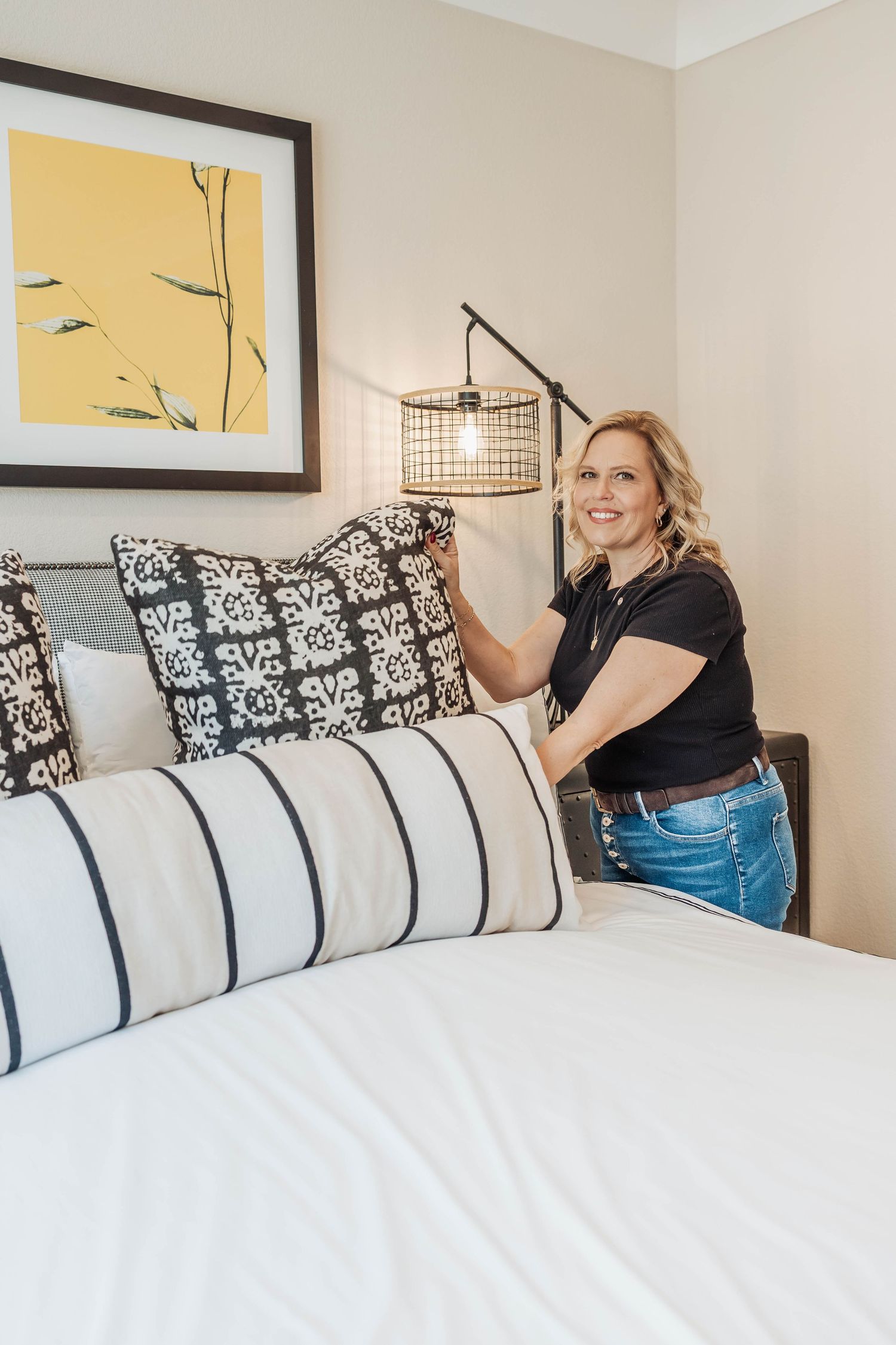 Bedroom interior with white bedding, decorative pillows and wall art.