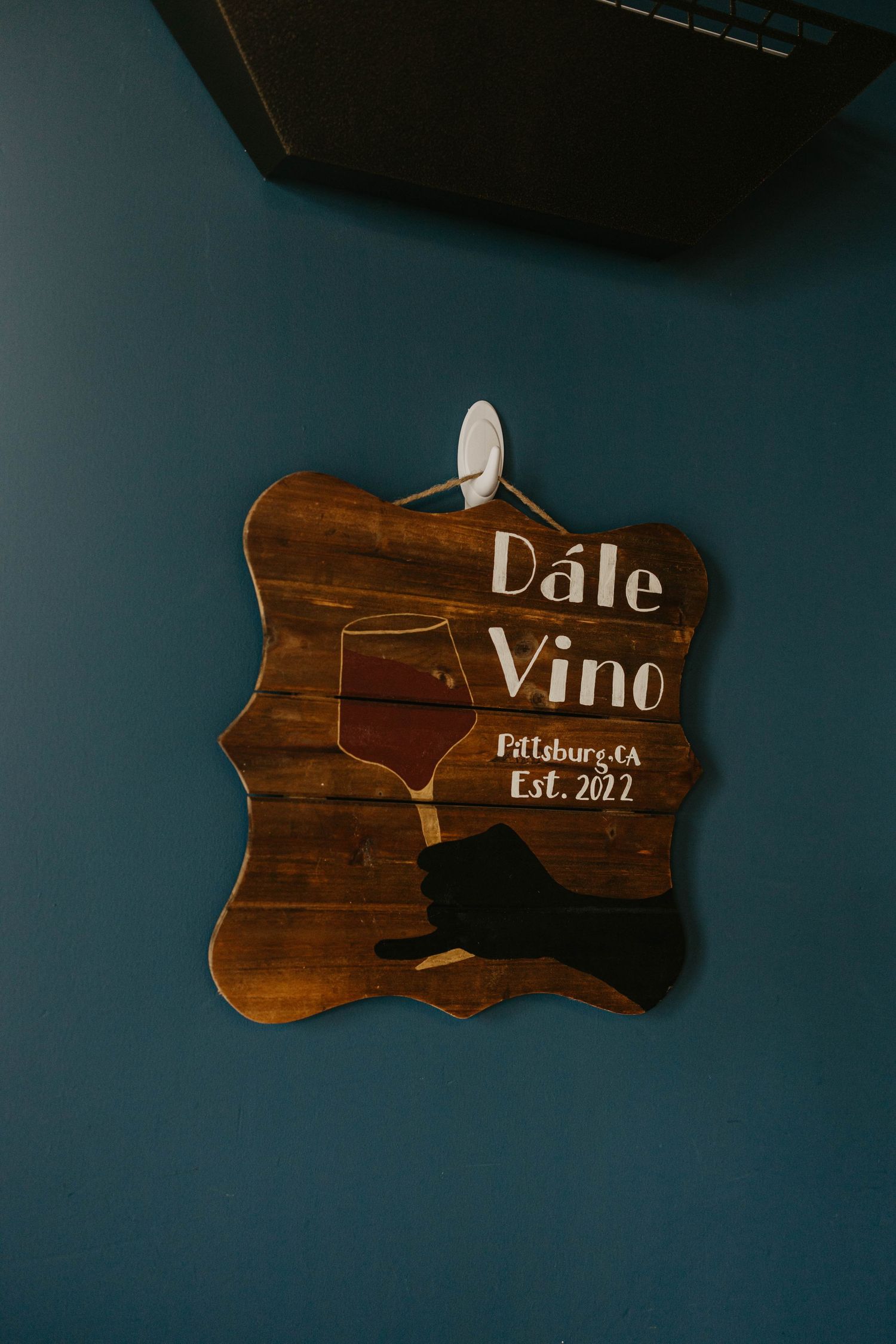 Wooden wall sign reading 'Dale Vino Est. 2022' against dark blue background.