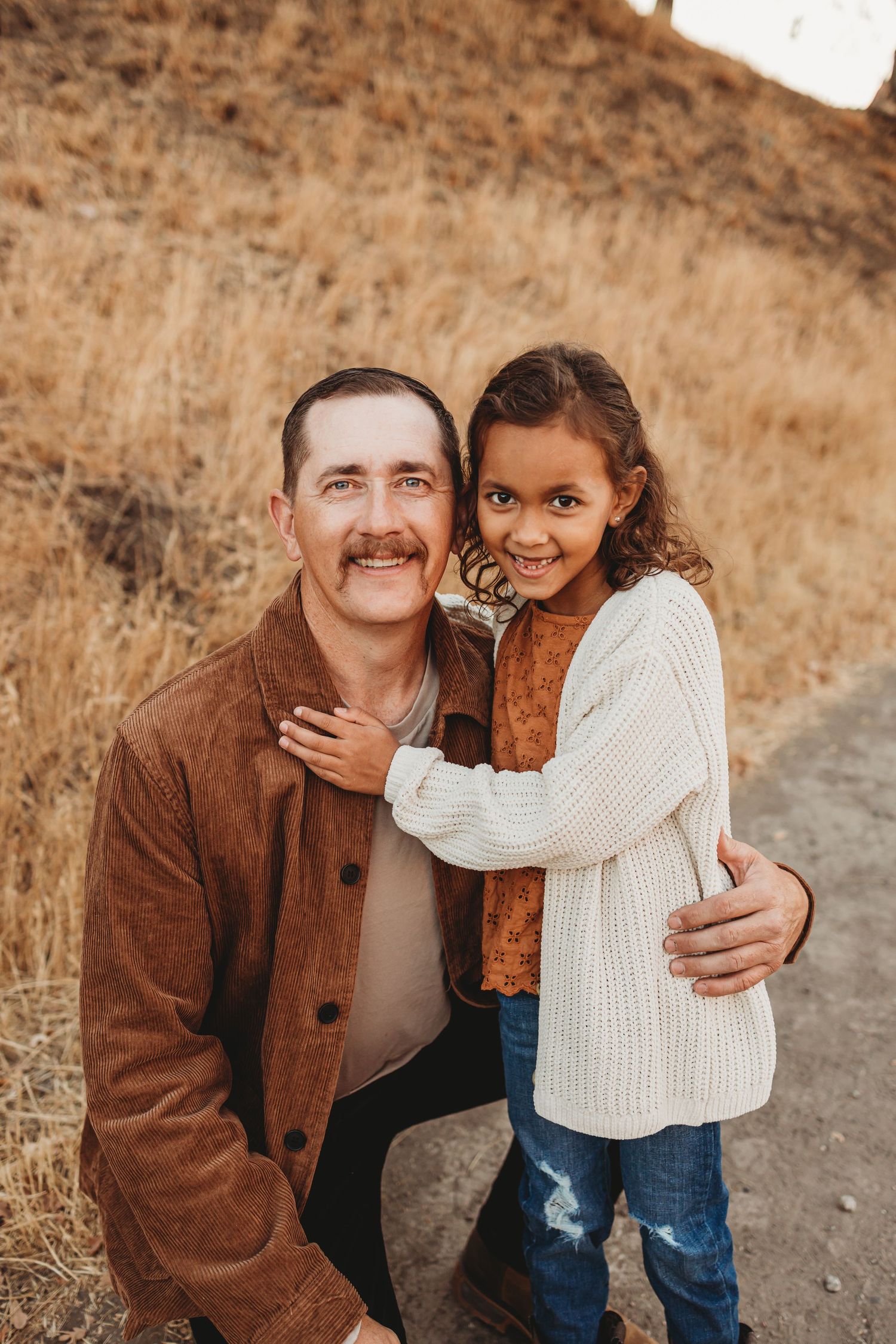 Parent and child smiling together on nature trail during golden hour portrait session.