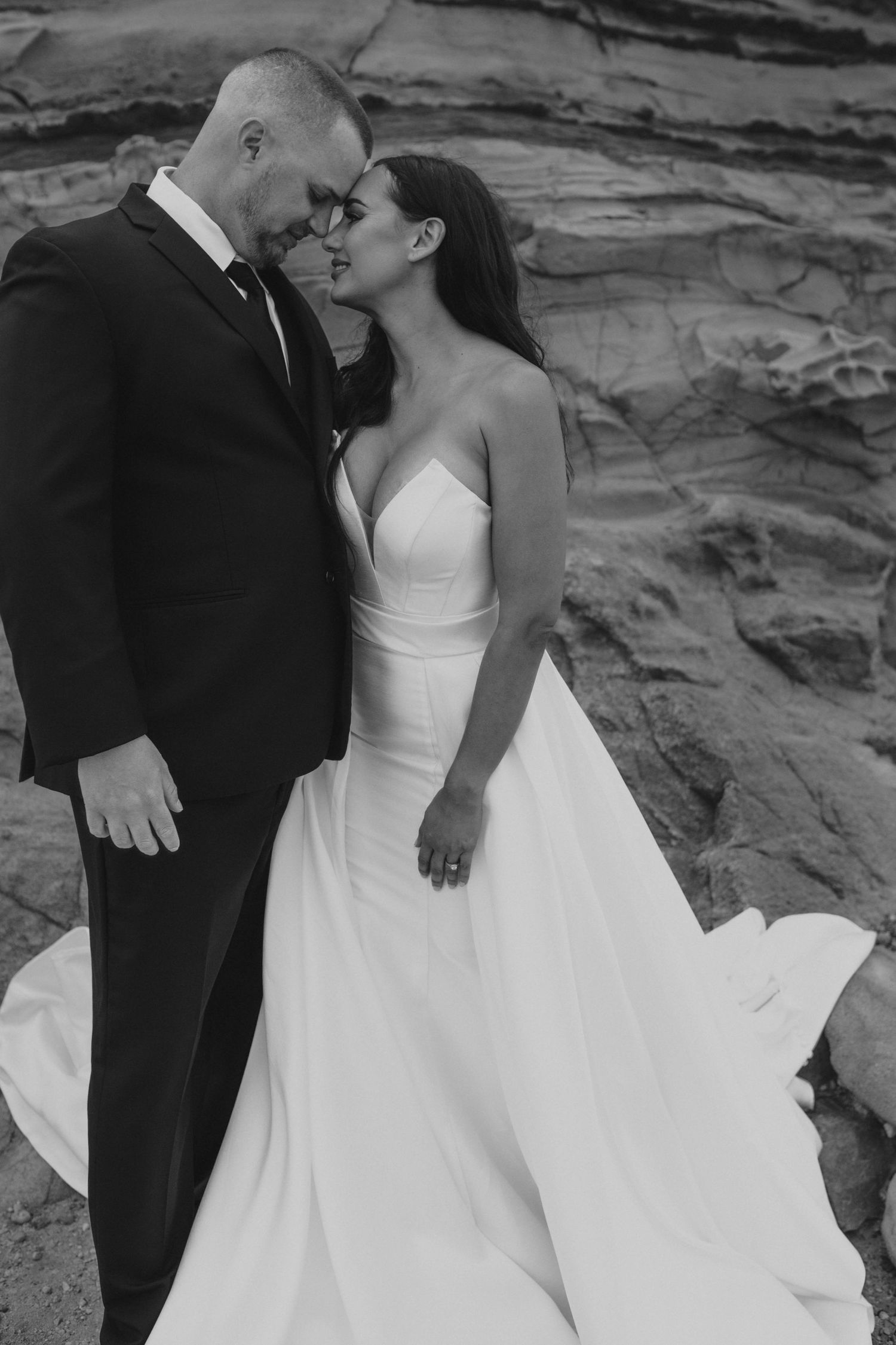 An intimate black and white wedding portrait against textured rock formations.