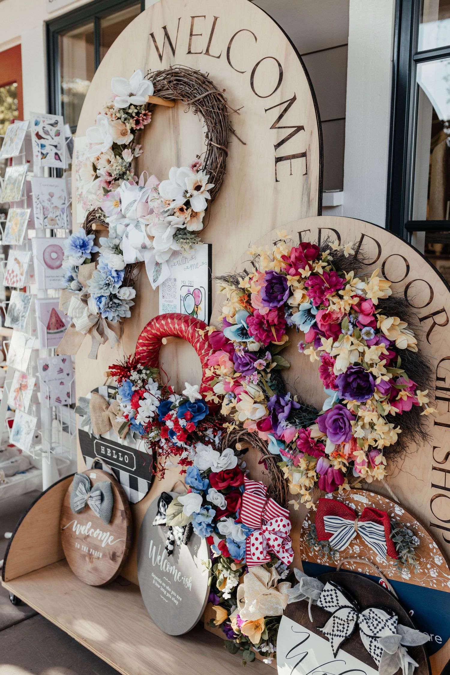 Decorative welcome sign with floral wreaths and retail merchandise displayed at store entrance.