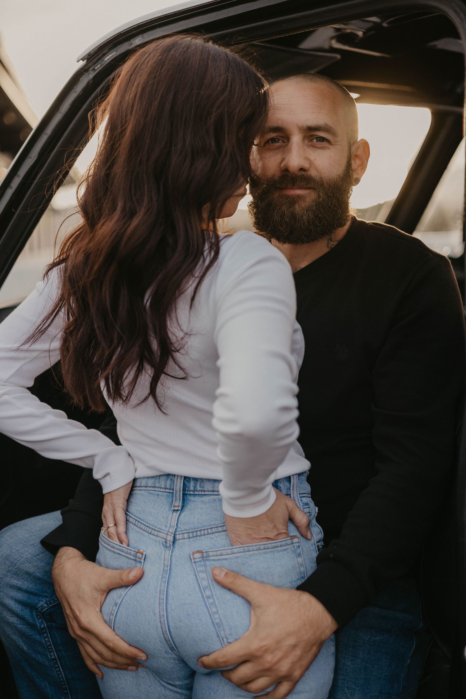 Intimate moments captured between couple in casual wear inside vehicle.