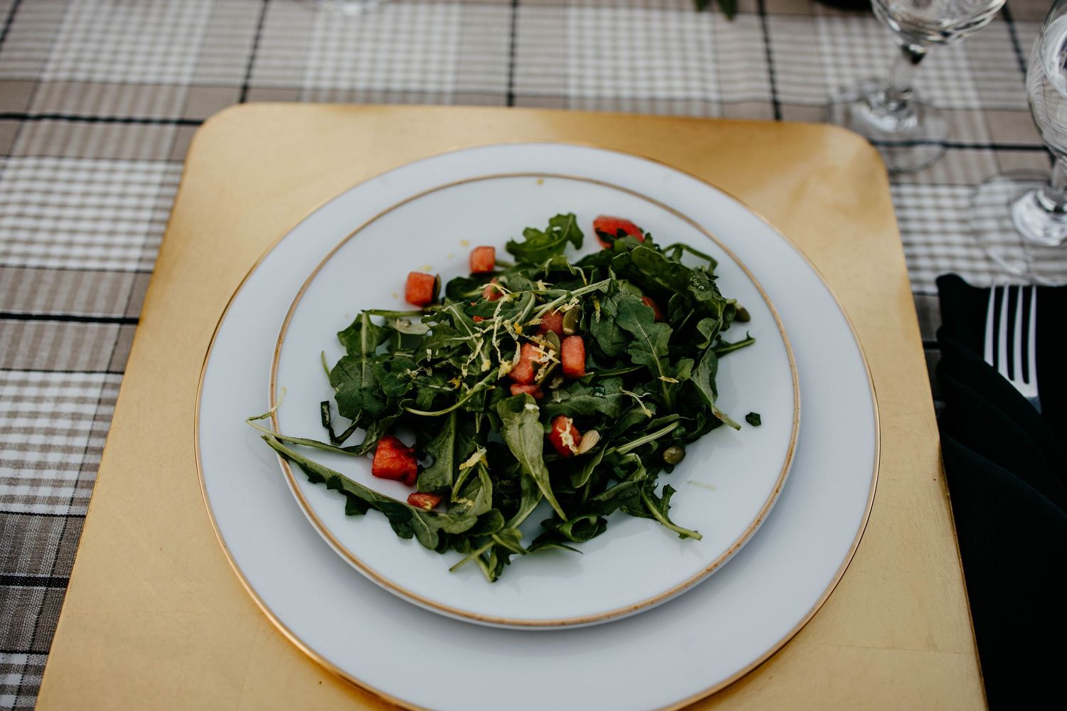Fresh green salad with red garnishes served on white plates.