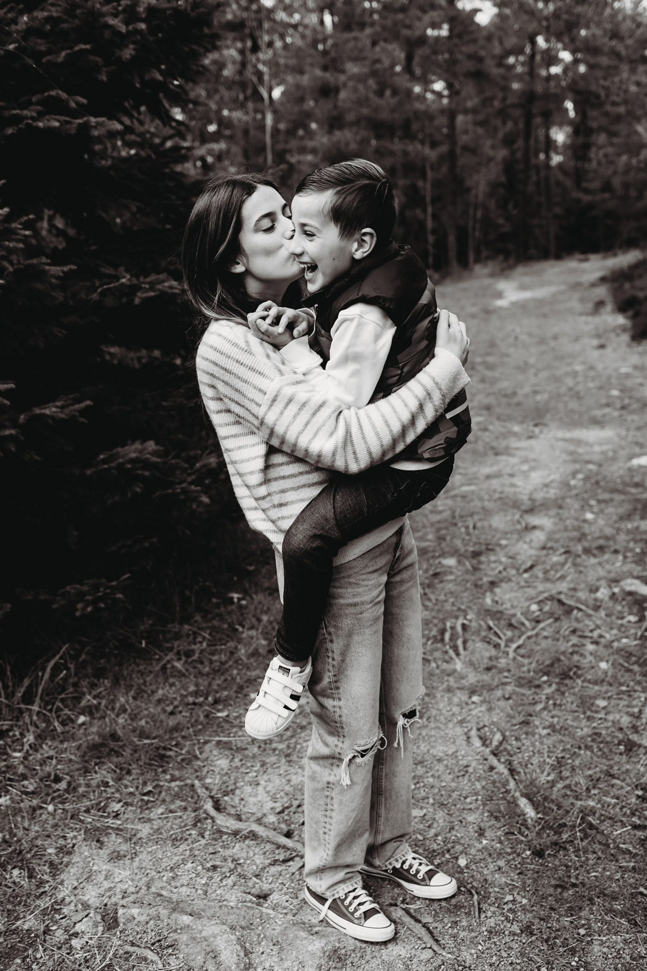 A joyful embrace between parent and child on a forest path in black and white.