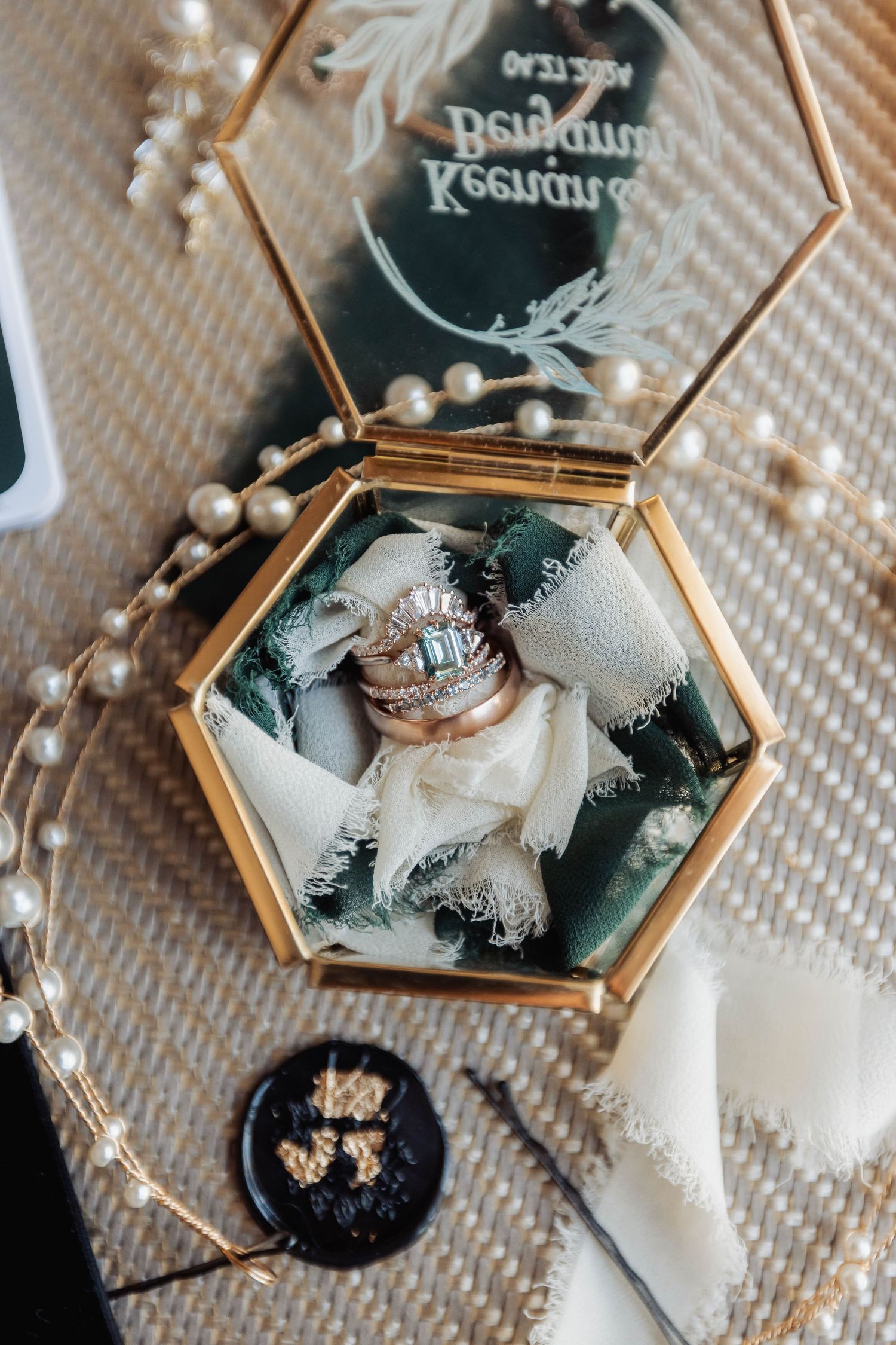 Vintage-style hexagonal jewelry box displaying wedding rings on textured fabric.