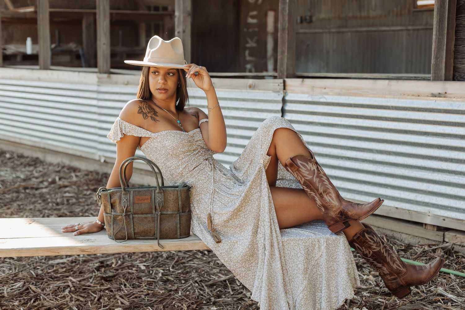 Rustic fashion accessories including tan hat and leather bag in outdoor setting.