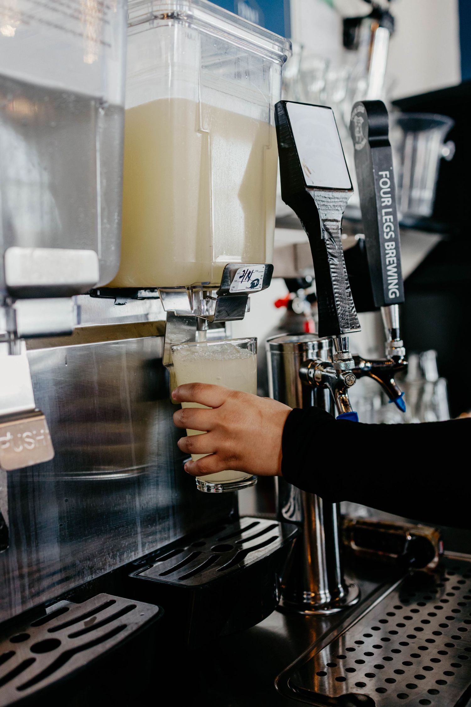 Close up of hands operating espresso machine dispensers with creamy liquid.