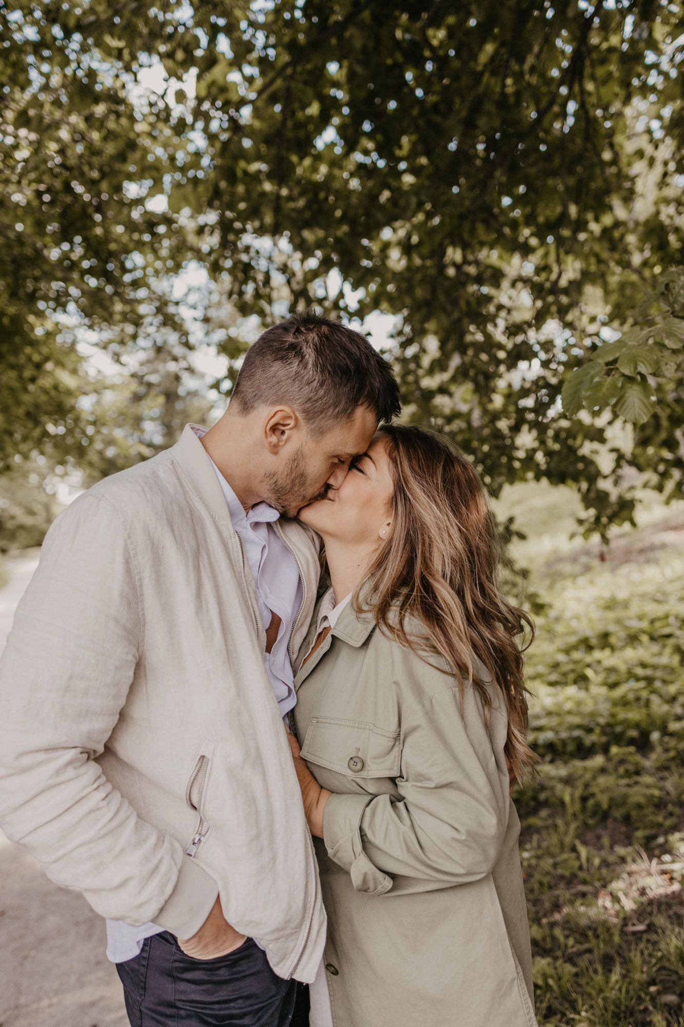 Intimate moment between couple sharing tender kiss on nature path.