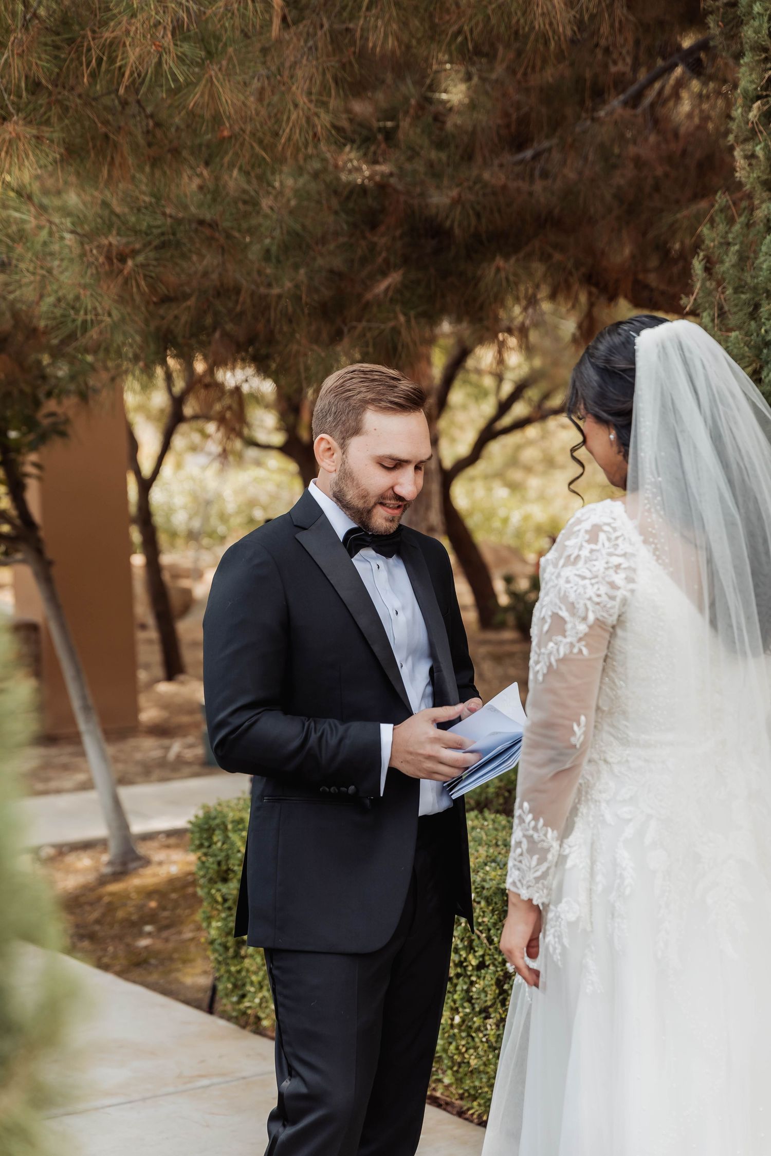 Wedding couple exchanging vows or reading letters outdoors.