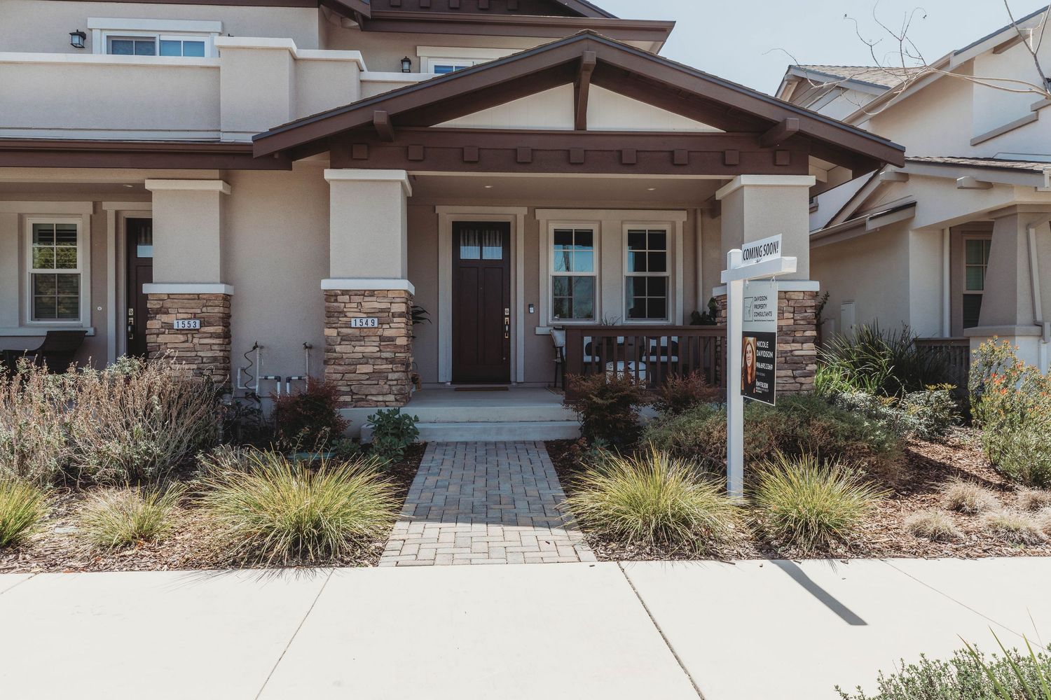 Exterior view of modern residential homes with desert landscaping and paved driveways.