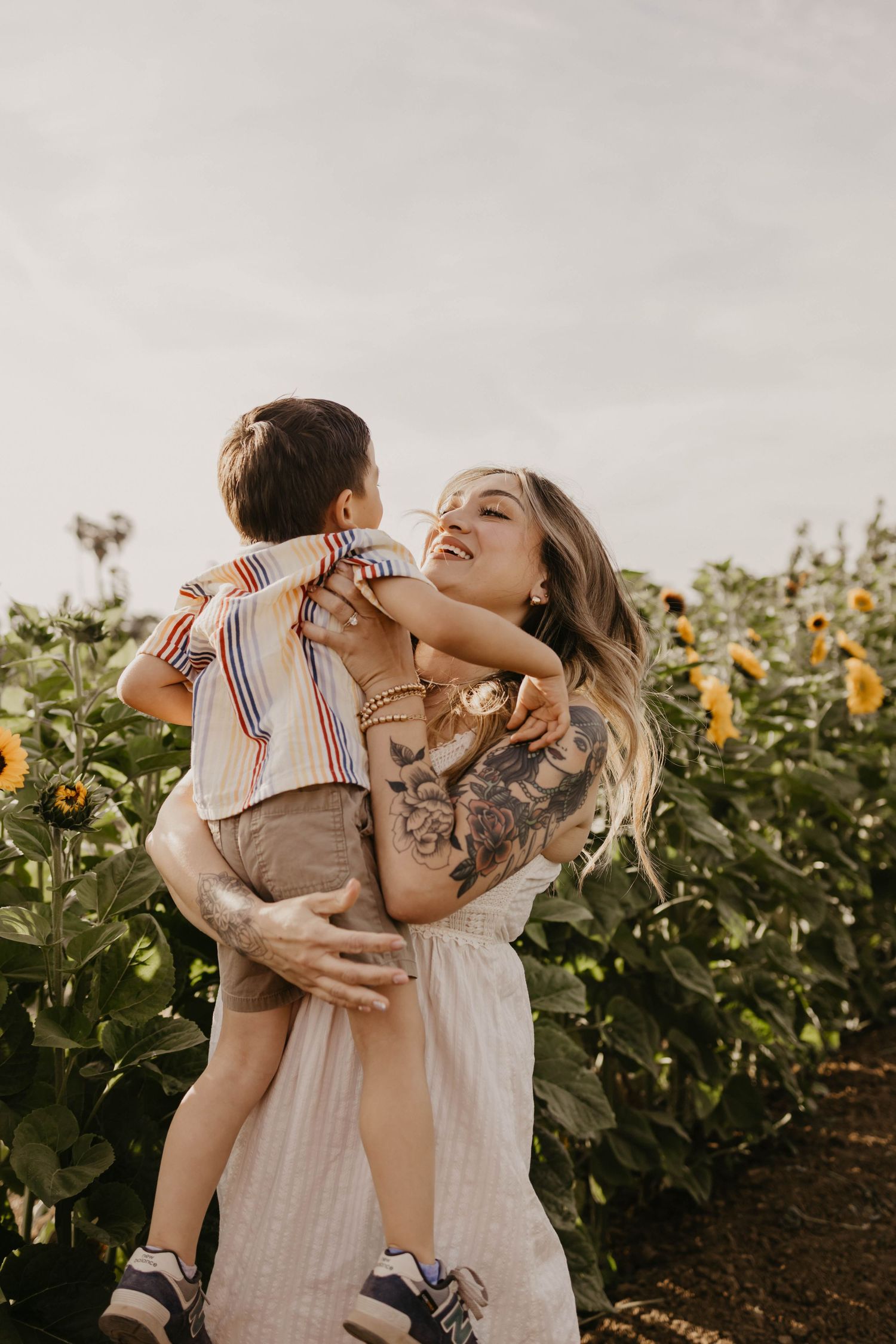 Joyful family shares laughter and hugs in a blooming sunflower field at sunset.