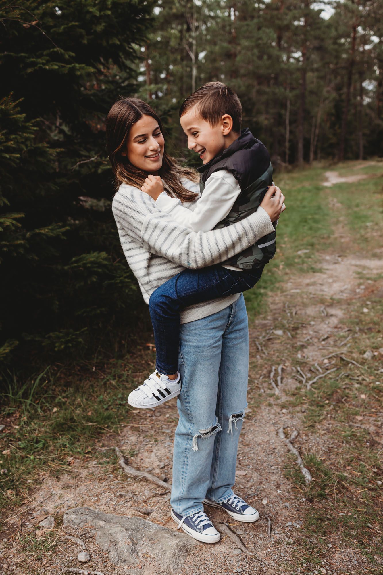 A playful moment between parent and child while hiking through a pine forest.