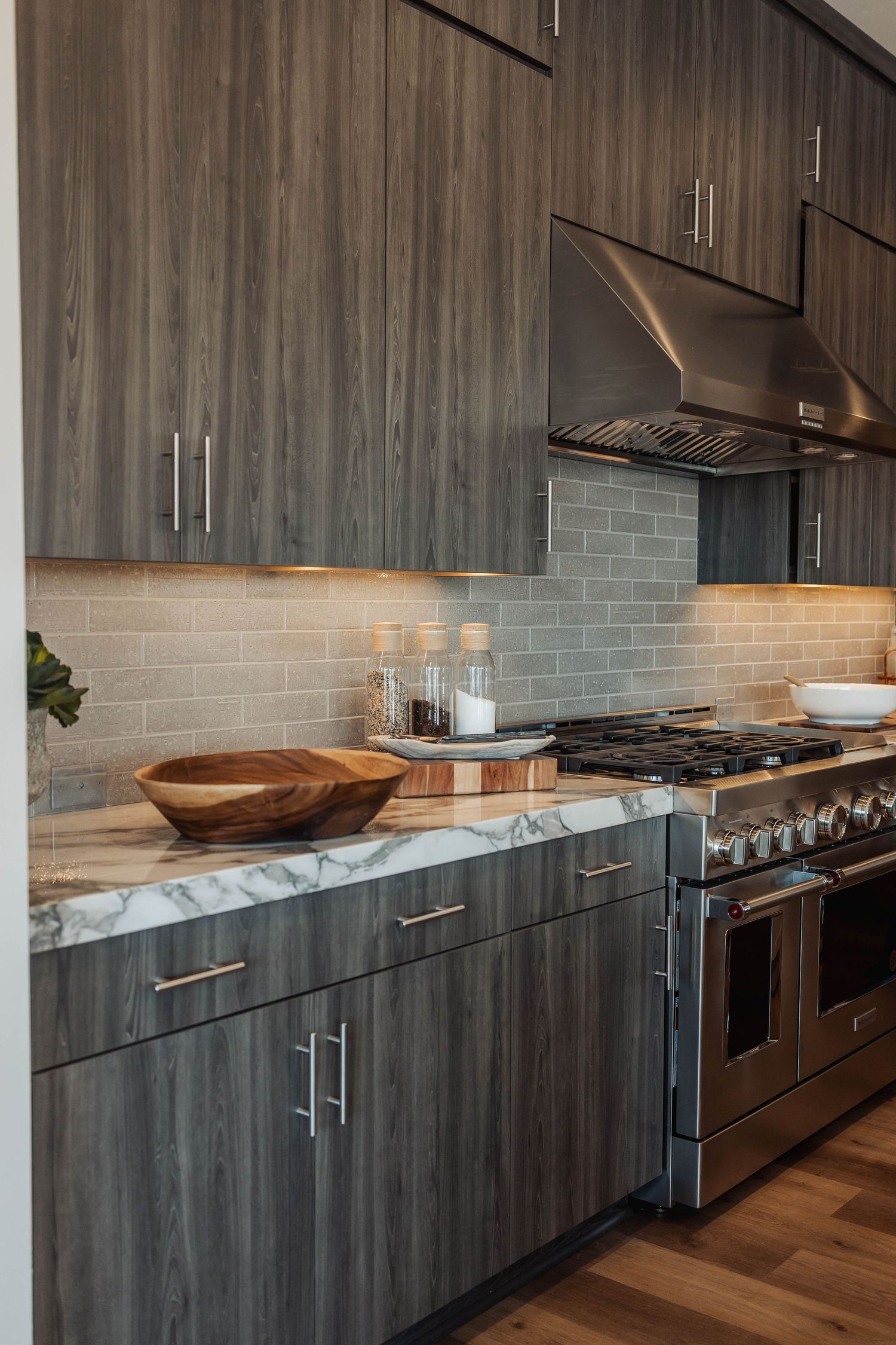 Contemporary kitchen with dark wood cabinets, marble countertops, and stainless steel appliances.