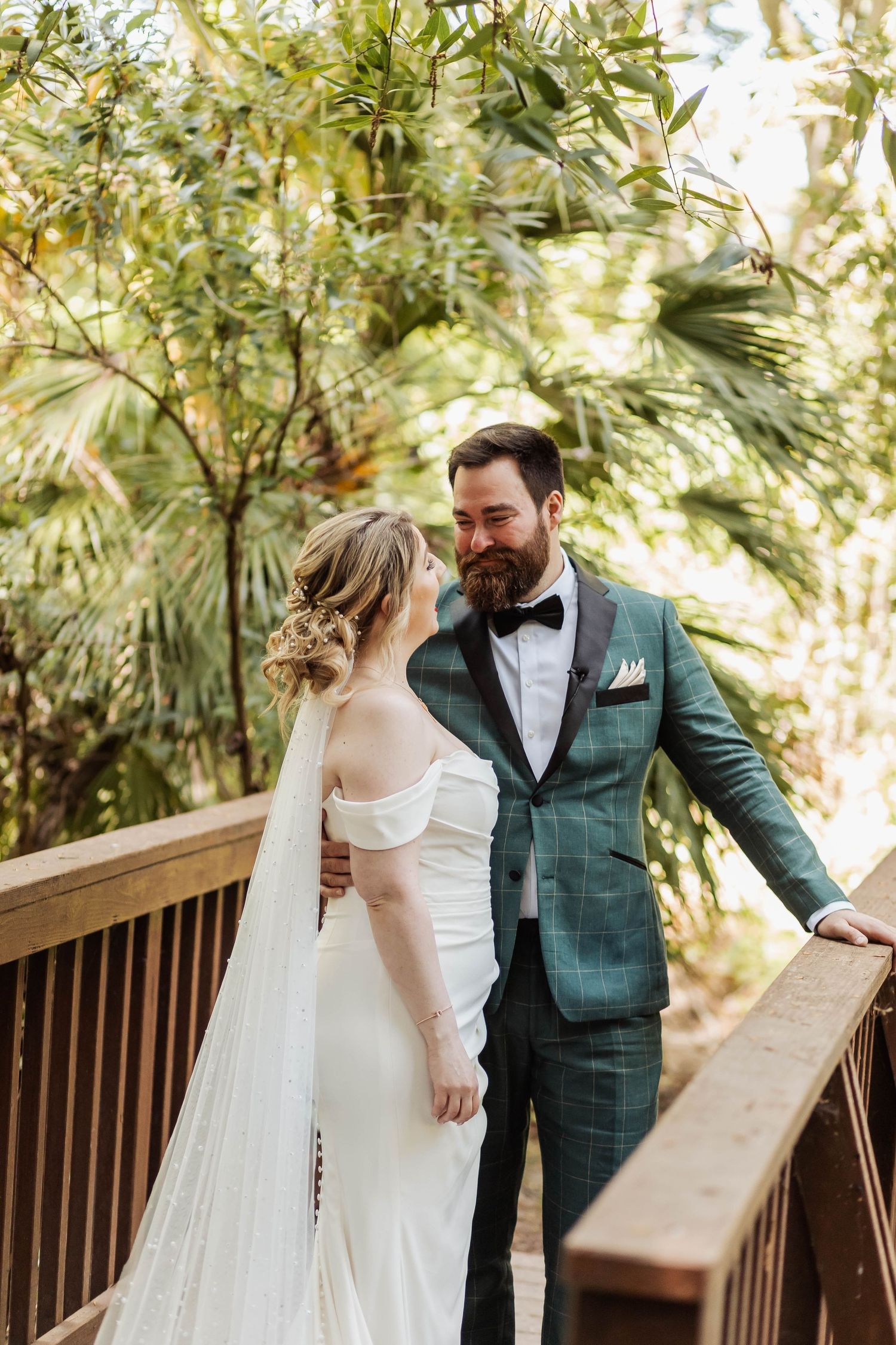 Wedding couple sharing intimate moments on a wooden deck surrounded by lush greenery.