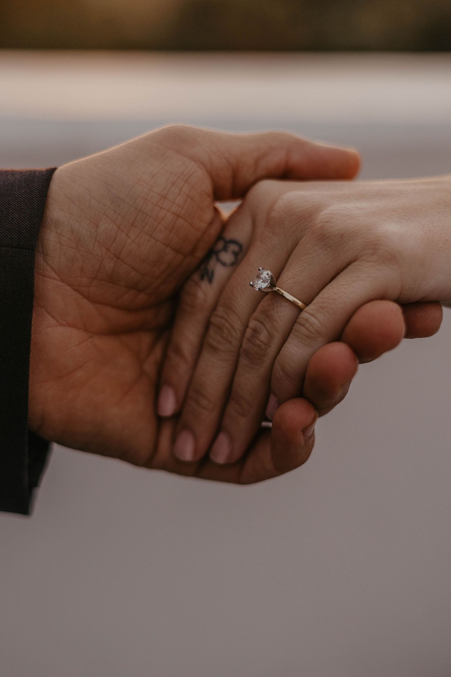Close-up of hands with engagement ring showing a tender moment between a couple.