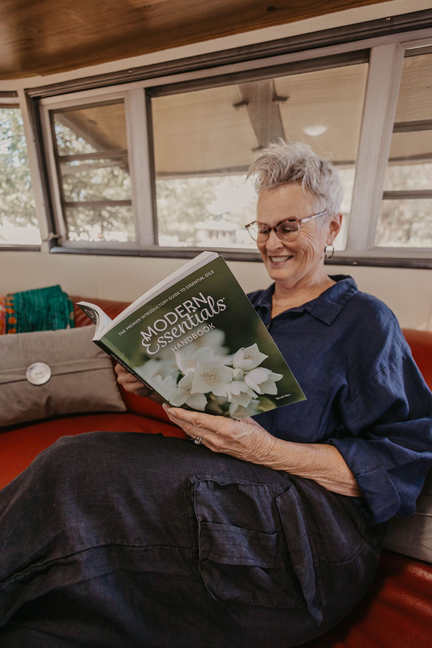 Person reading a book while relaxing on red leather couch.