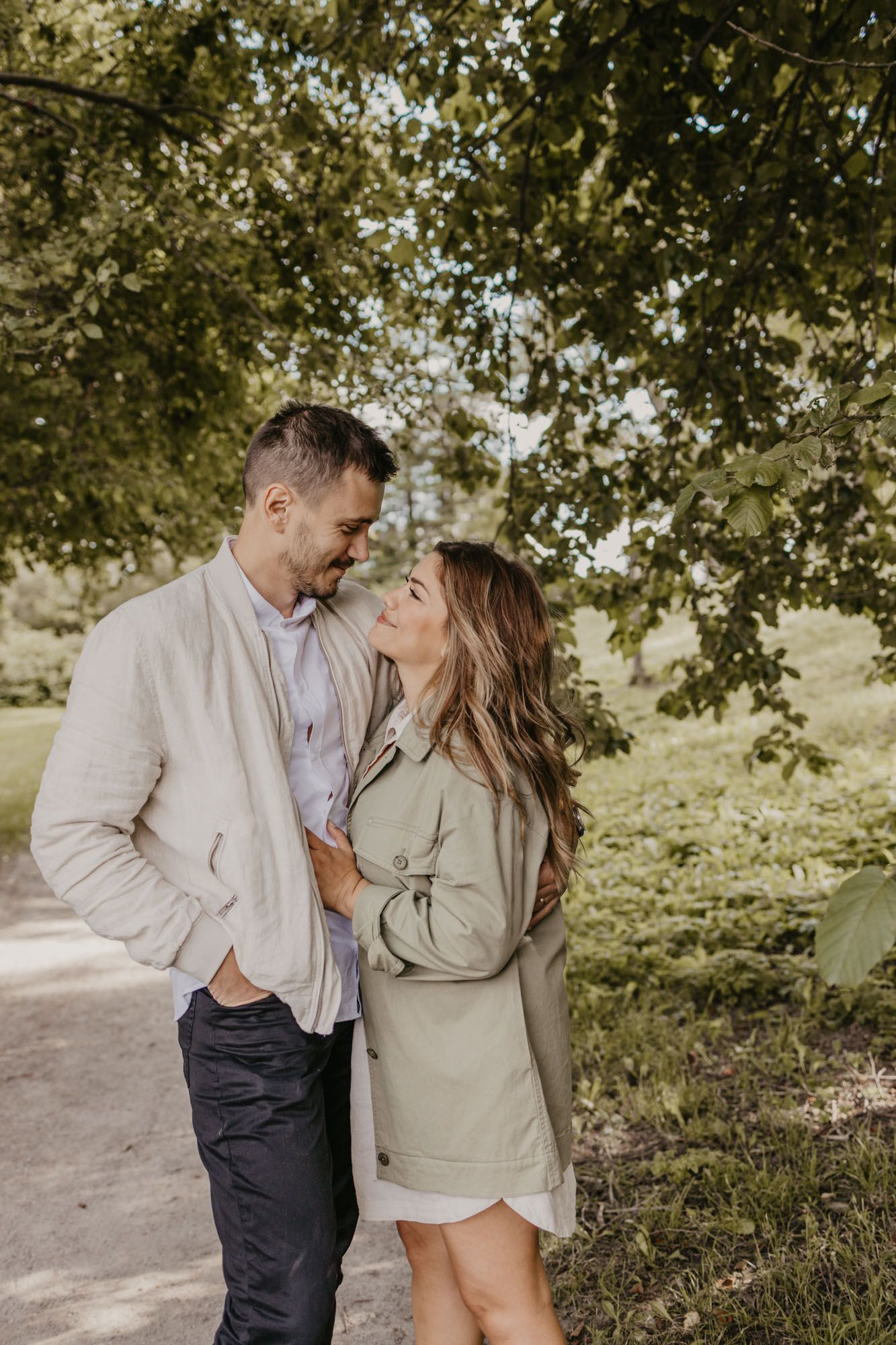 Romantic couple portrait in coordinated neutral outfits on outdoor walking path.