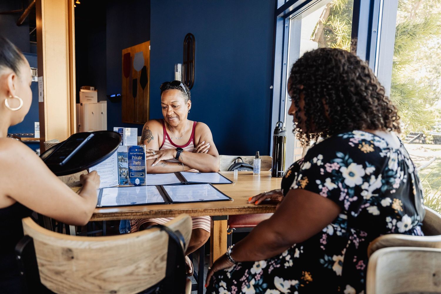 Business meeting taking place at a casual restaurant table with paperwork and drinks.