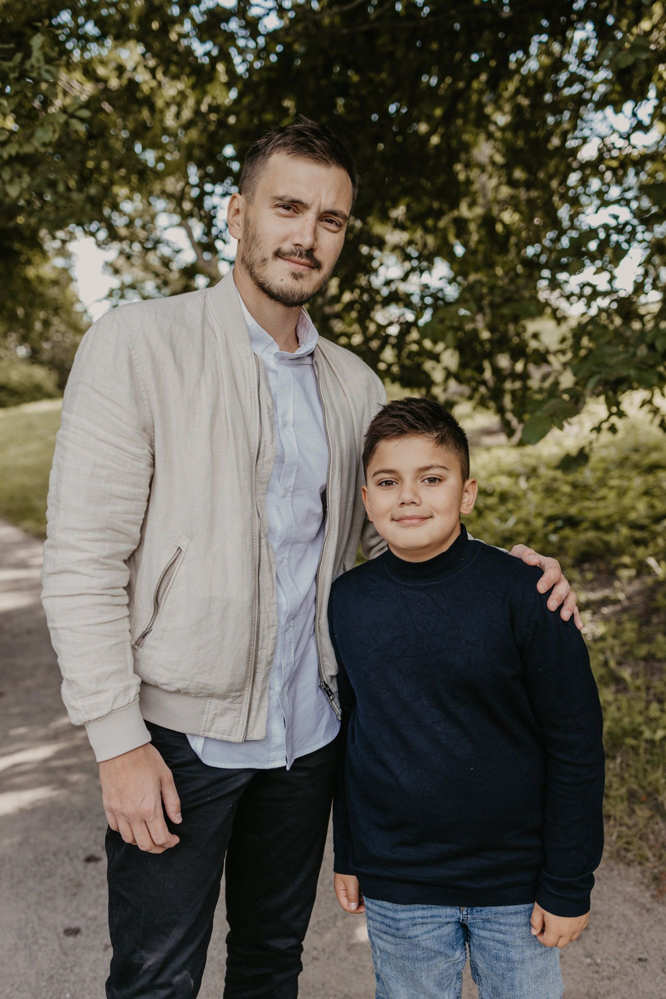 Casual outdoor portrait of two people in coordinating navy and beige outfits on a path.